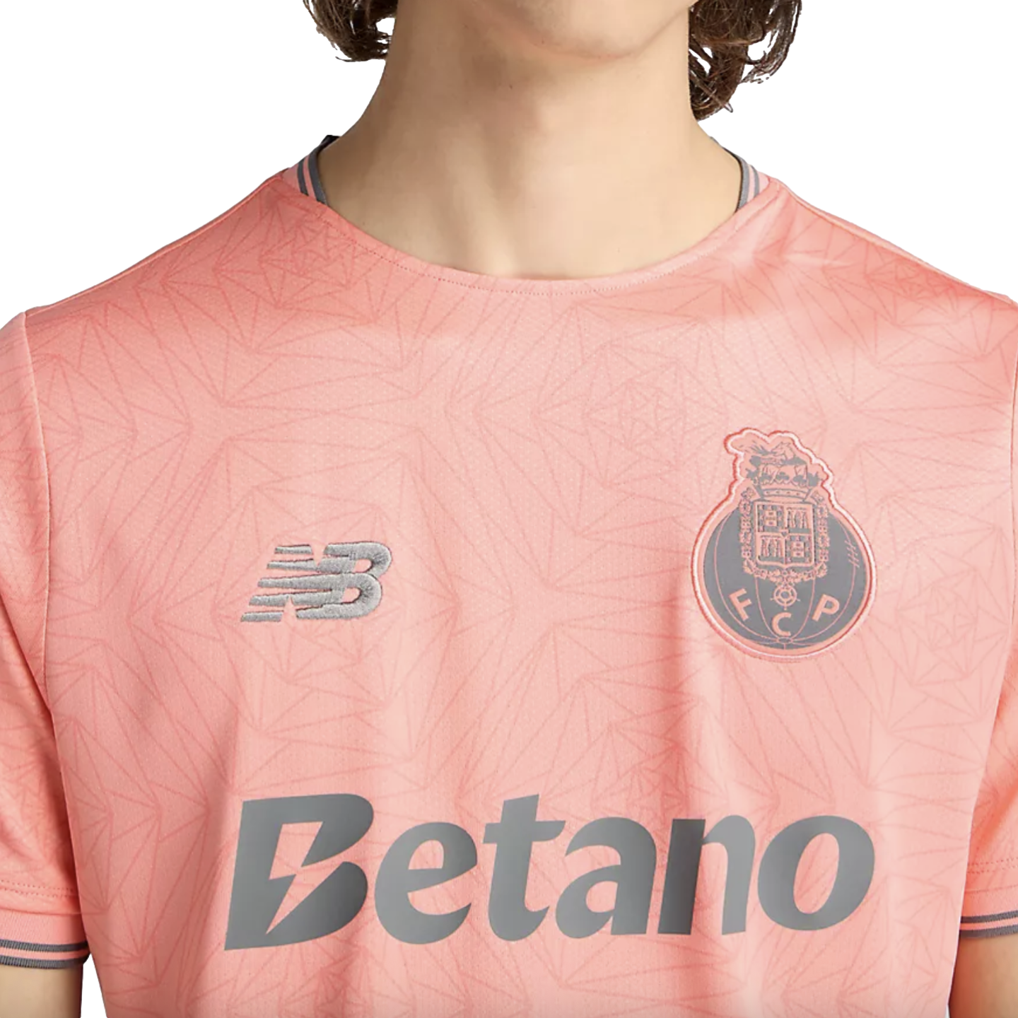 Close-up of a person wearing a pink New Balance soccer jersey for FC Porto, featuring the club crest and Betano sponsor logo.