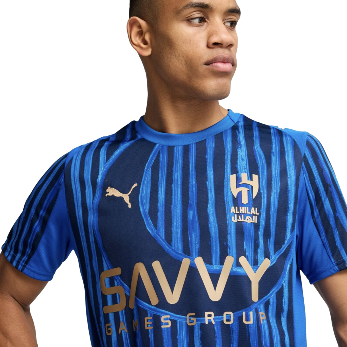 A young man wearing a blue Puma Al-Hilal soccer jersey with "SAVVY GAMES GROUP" printed on the chest.