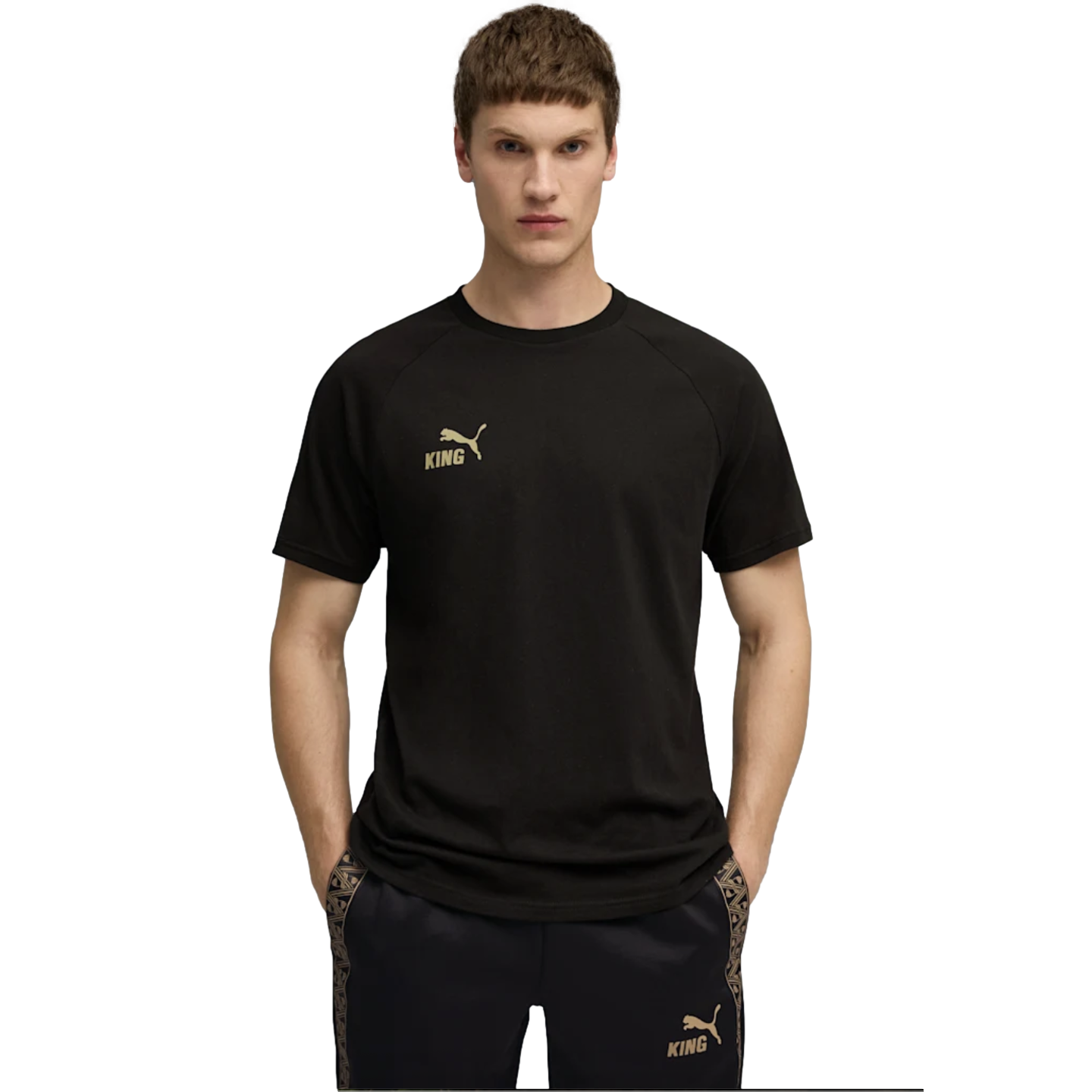 A man in a black Puma "King" t-shirt and matching shorts with gold logos, standing against a black background.