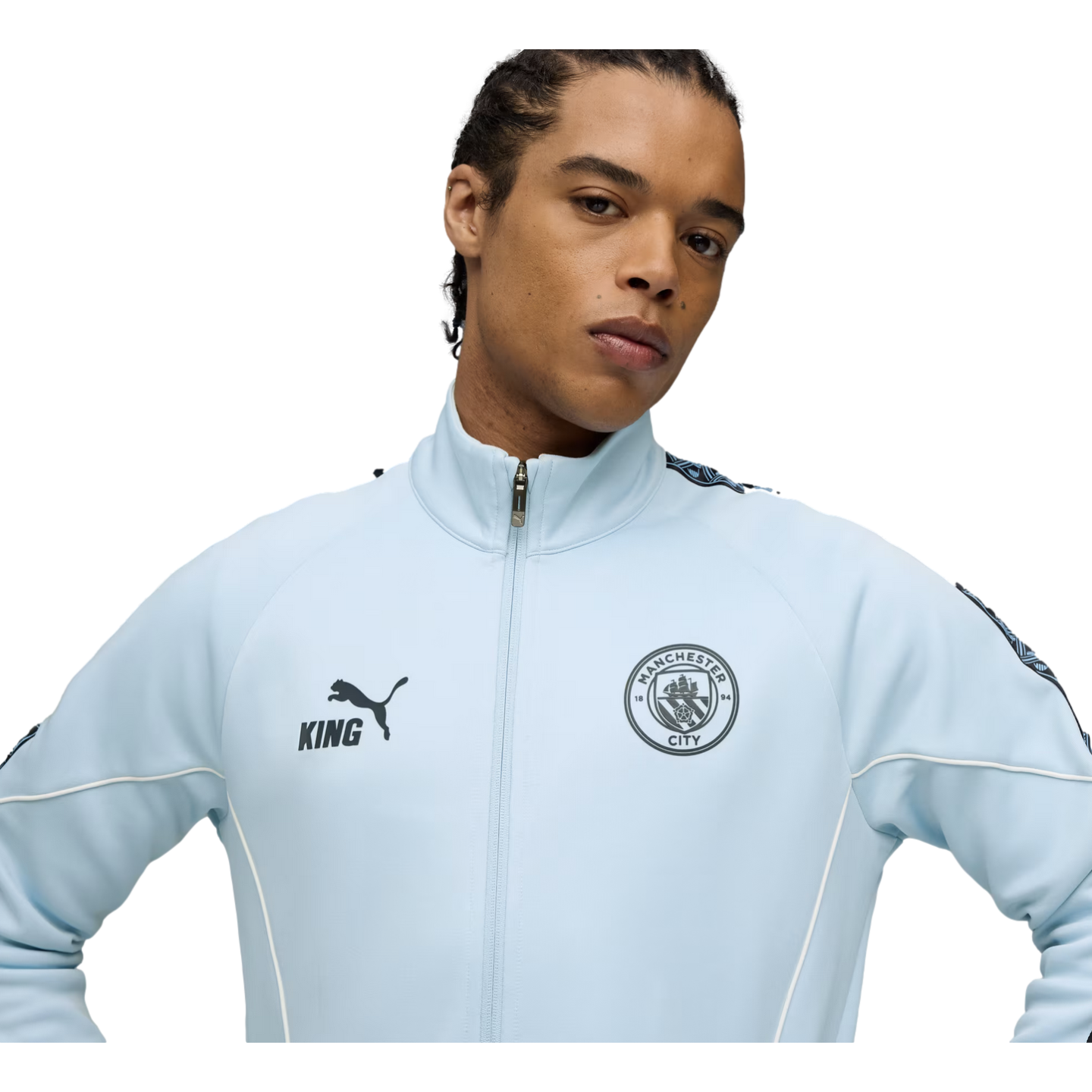 A man in a light blue Manchester City zip-up jacket with the Puma logo and club crest against a black background.