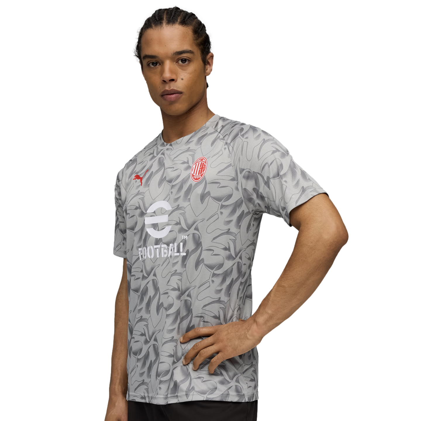 Man in a gray AC Milan training jersey with a leaf pattern and sponsor logos, posing against a black background.