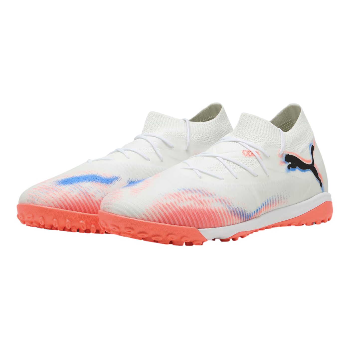 A pair of Puma turf soccer shoes in white, featuring pink and blue gradient designs and a bright coral pink lugged sole, isolated against a black background.