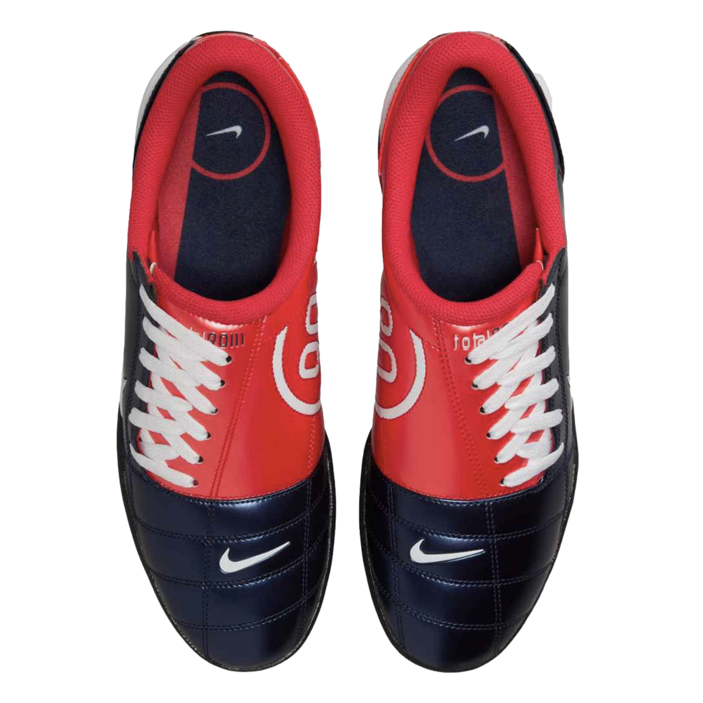 Top-down view of red and navy blue Nike Total 90 soccer cleats with white laces, white swoosh logos on the toes, and a large 90 logo on the sides.