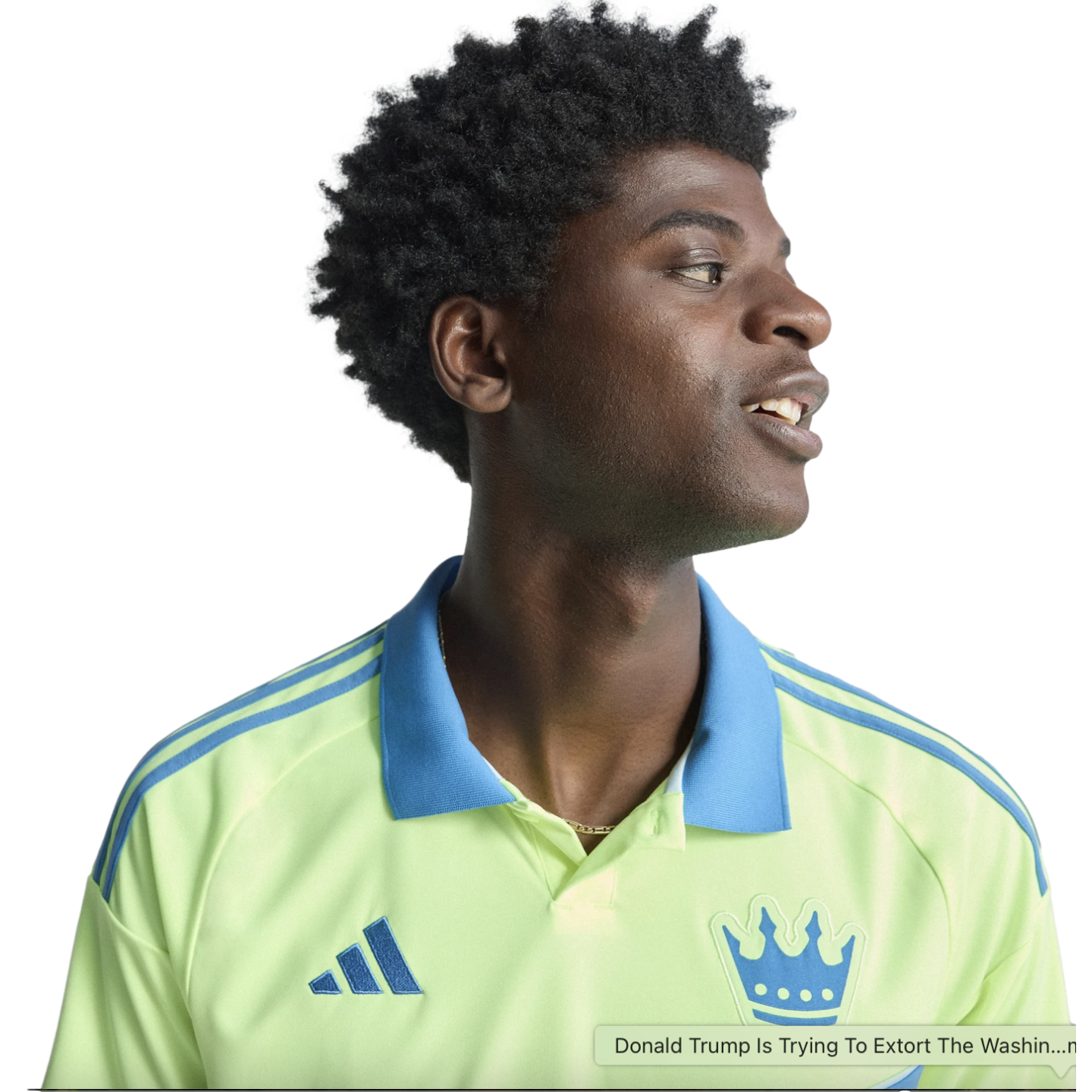 Profile of a smiling young Black man with an afro wearing a lime green Adidas polo shirt with a blue collar and crown logo, against a black background.