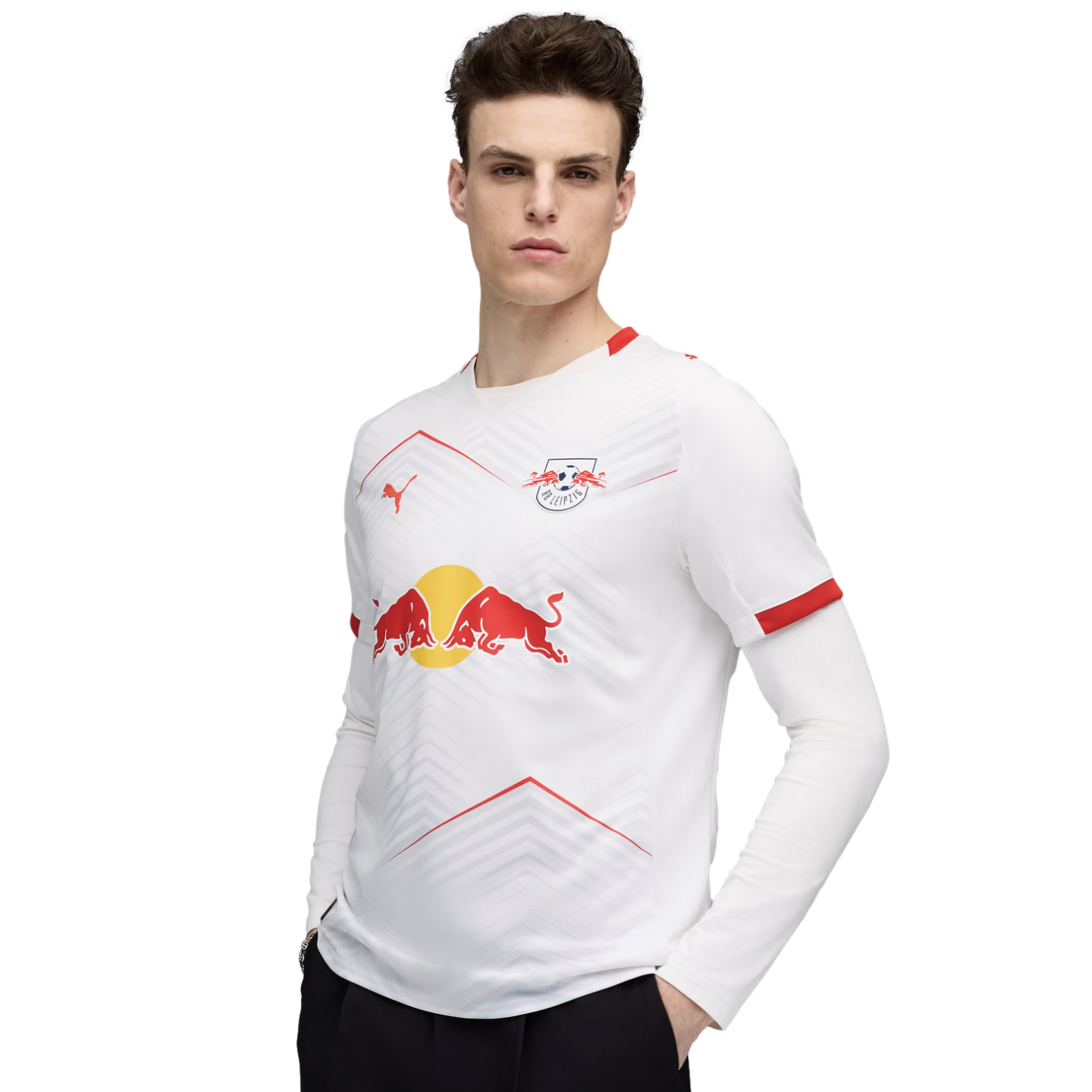 A man in a white RB Leipzig long-sleeve soccer jersey featuring the Red Bull logo, posing against a solid black background.