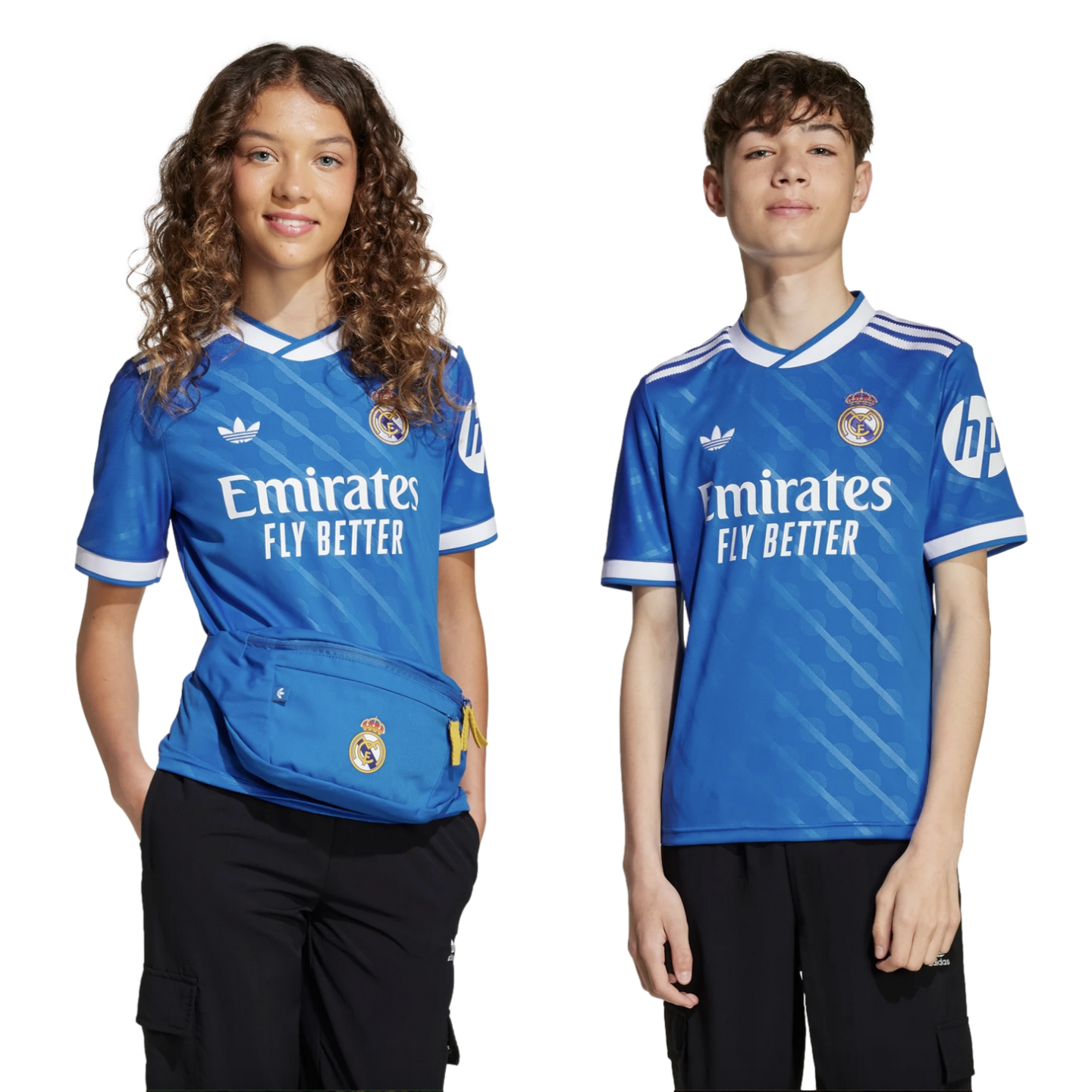 Two young people pose in blue Real Madrid jerseys and black pants against a black background. The girl on the left wears a matching blue waist bag.