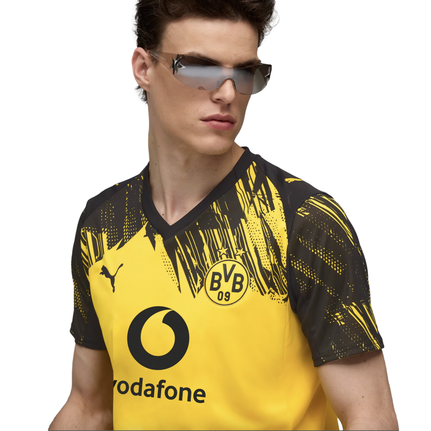 A man wears a yellow and black Puma BVB jersey and futuristic sunglasses against a black background.