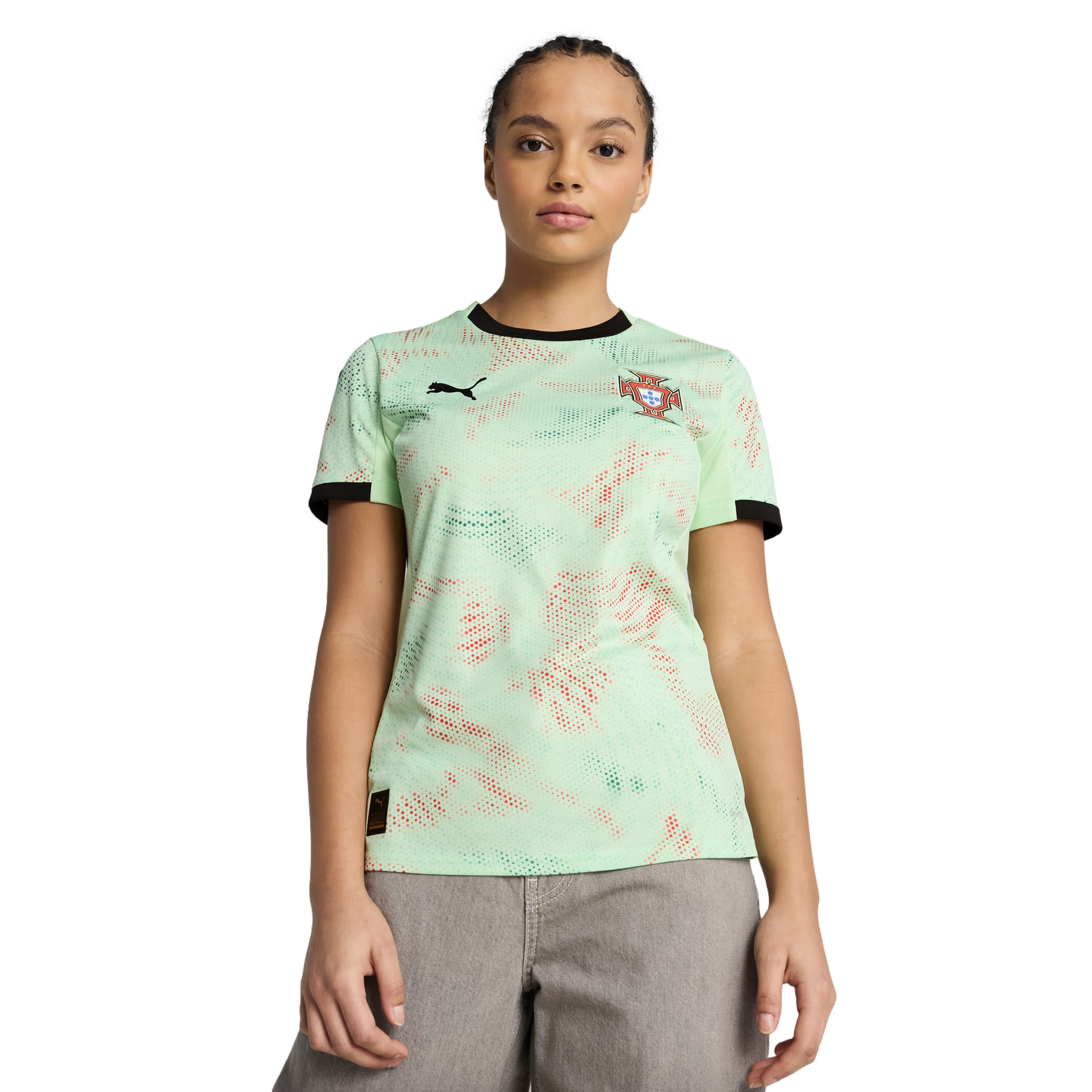 A woman in a mint green Portugal football jersey with a red and green pattern and grey pants, posing against a solid black background.