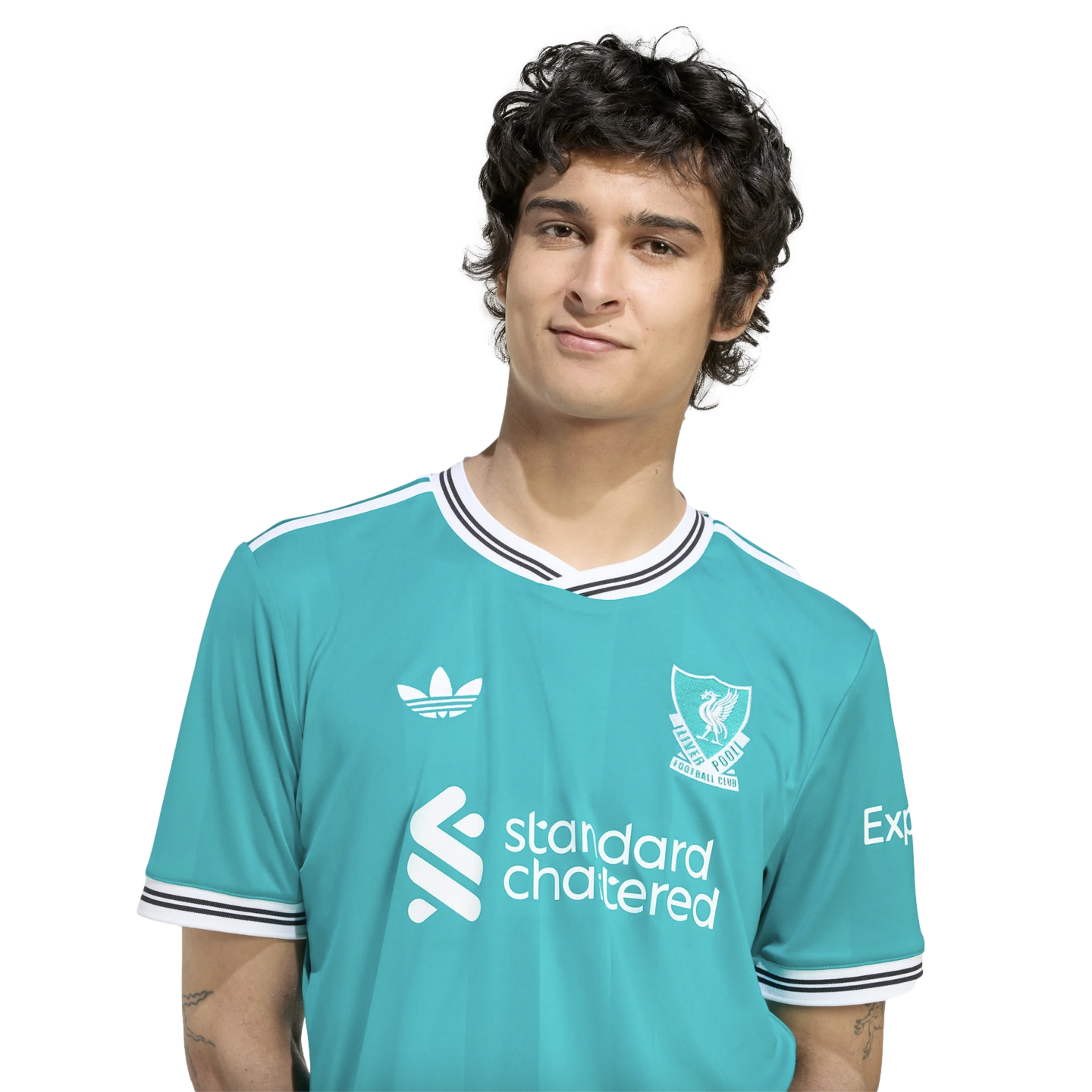 A young man with dark, wavy hair wears a teal Liverpool F.C. jersey against a solid black background.