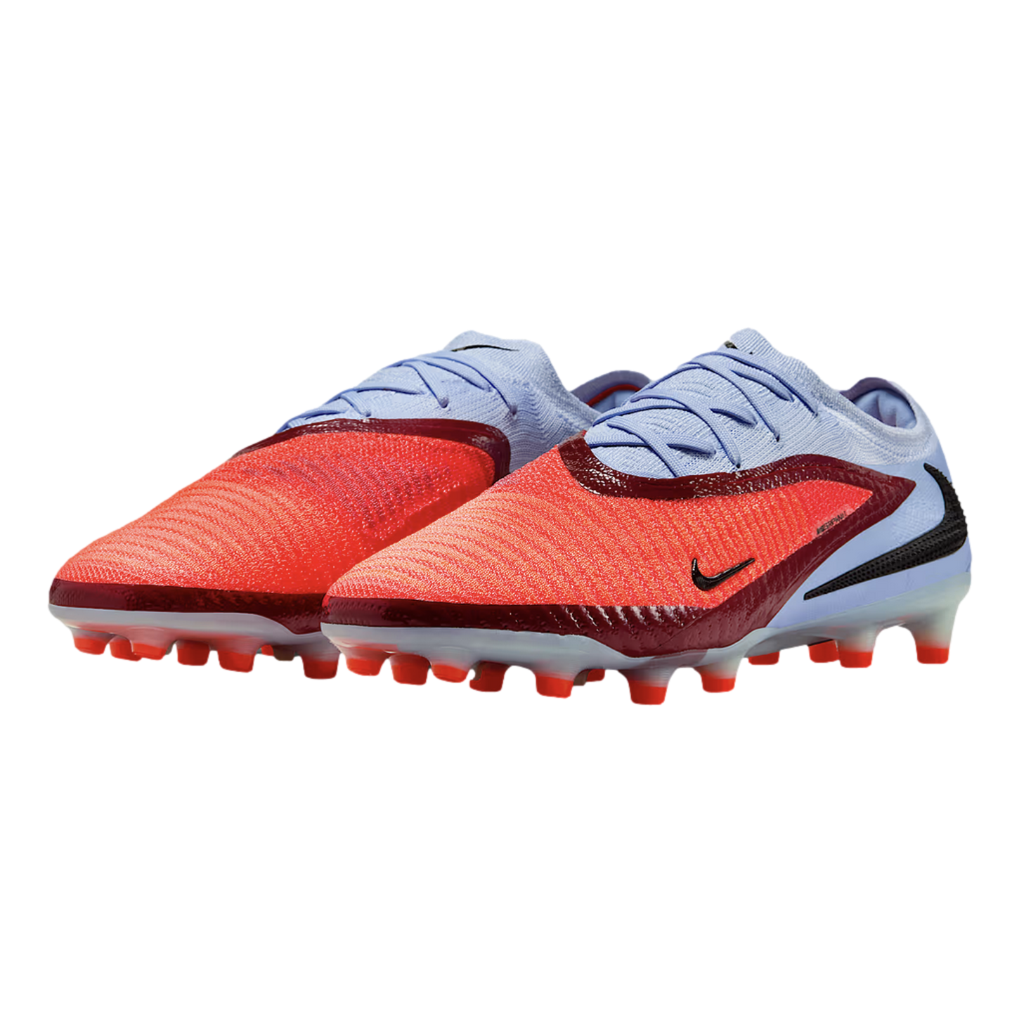 A pair of Nike soccer cleats featuring a light blue upper, bright orange knit forefoot, and dark red trim, displayed on a black background.