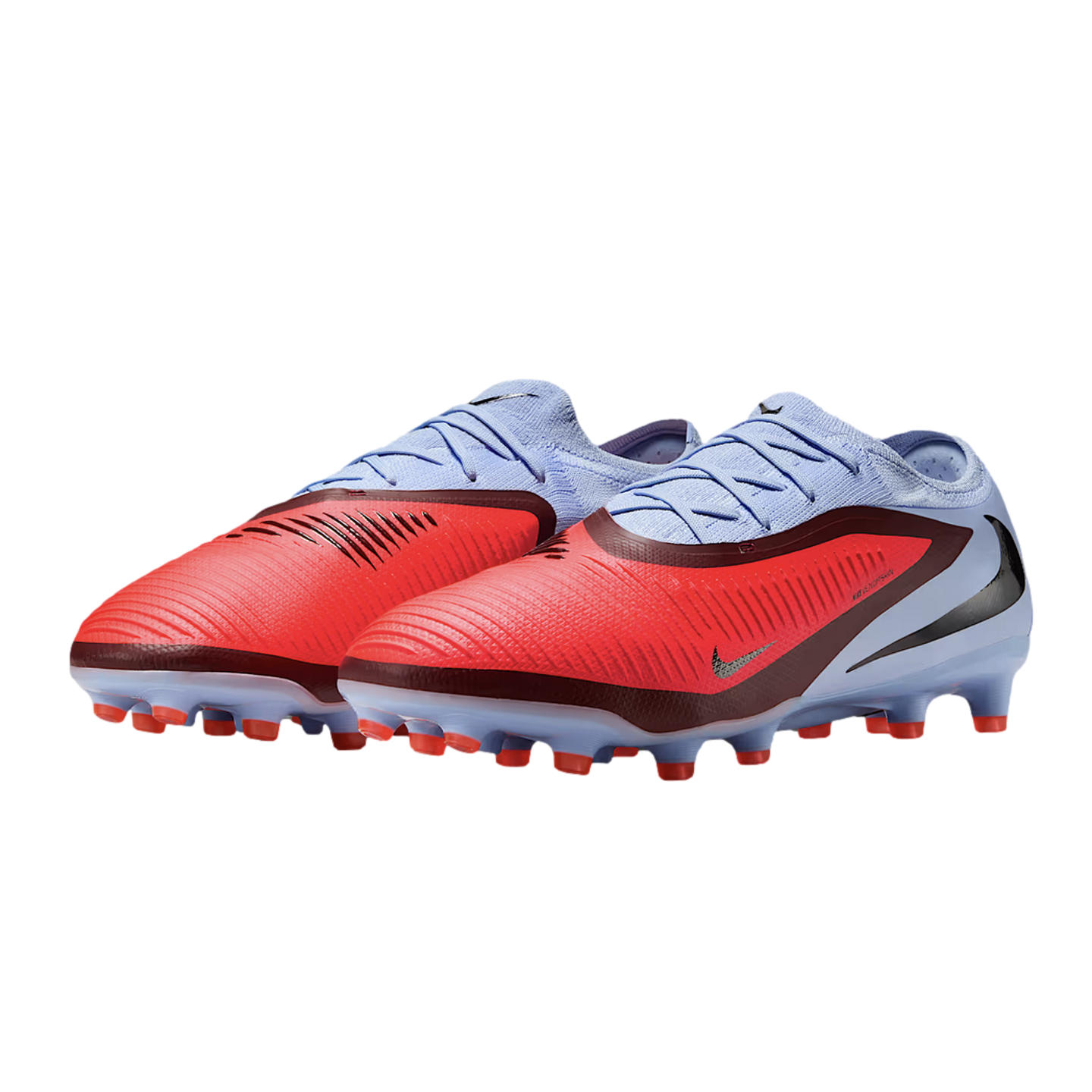 Light blue and red Nike Phantom Venom soccer cleats with a textured upper and red studs, isolated on a black background.