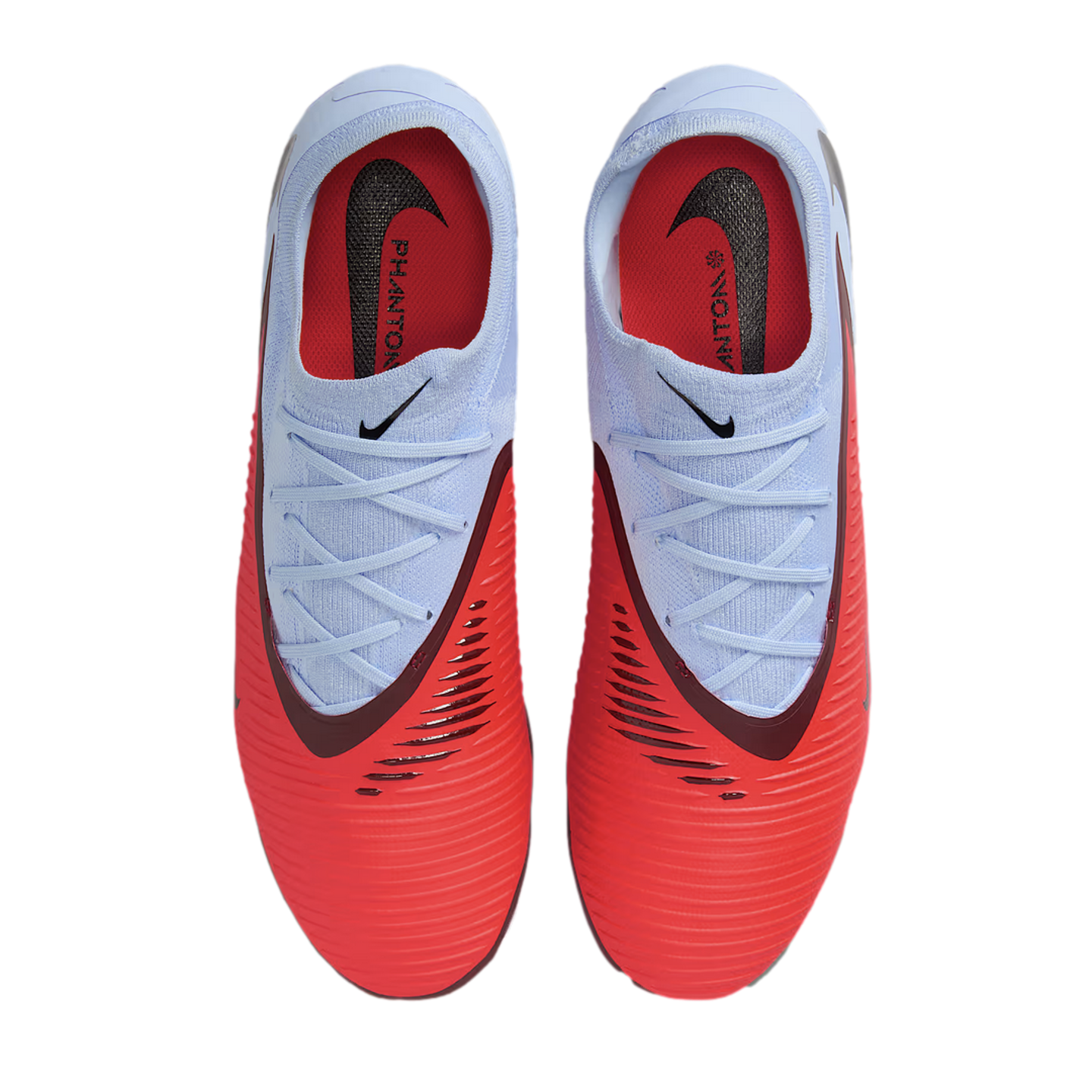 Top-down view of Nike Phantom soccer cleats featuring a light blue collar and lace area transitioning into a vibrant red textured forefoot, set against a solid black background.