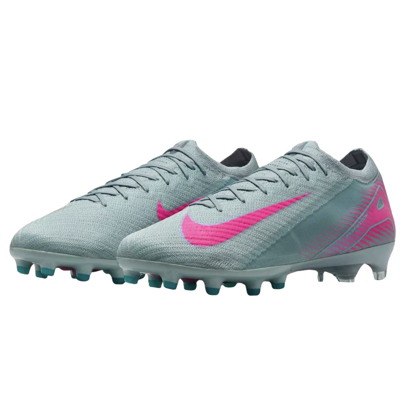 A pair of light grey Nike soccer cleats featuring vibrant pink swooshes and pink geometric patterns on the heels. The sole has teal and white studs, shown against a black background.
