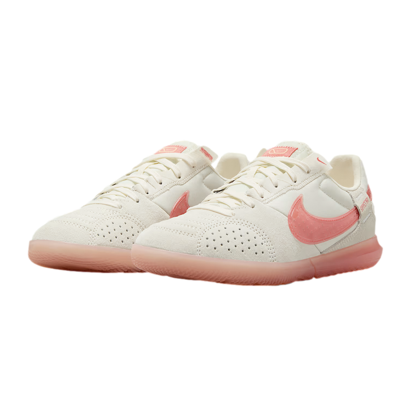 Pair of off-white Nike indoor soccer shoes with translucent pink swooshes and matching pink soles against a black background.
