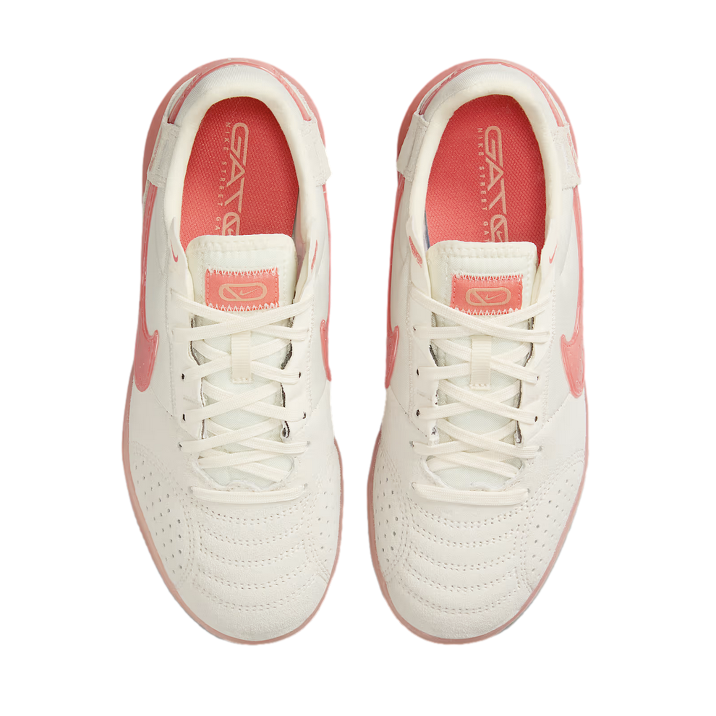 A top-down view of white Nike Street Gato sneakers with coral pink accents on the Nike swoosh, heel, and inner soles, set against a black background.