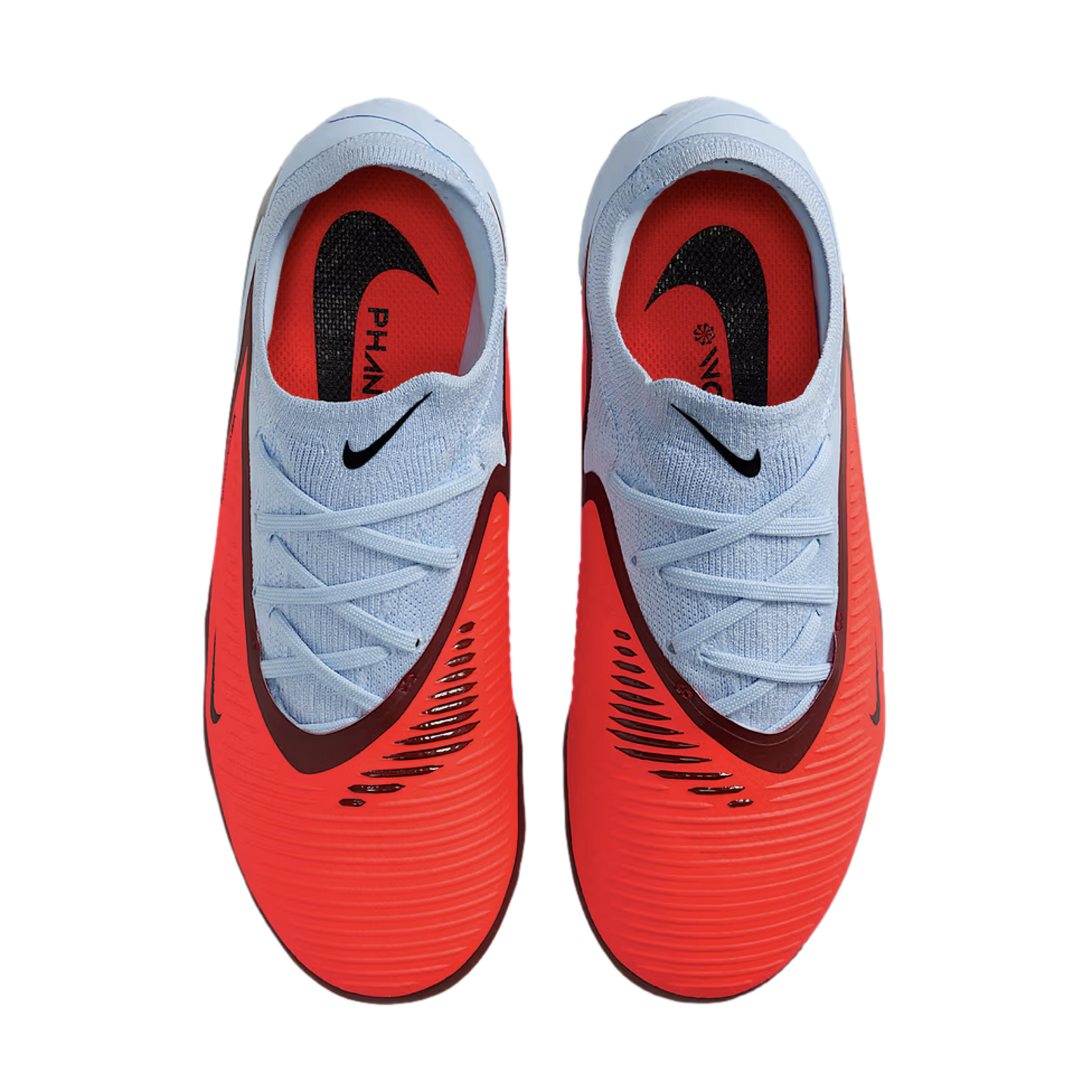 Top-down view of bright red and light blue Nike Phantom soccer cleats on a black background, featuring textured uppers and black swoosh logos.