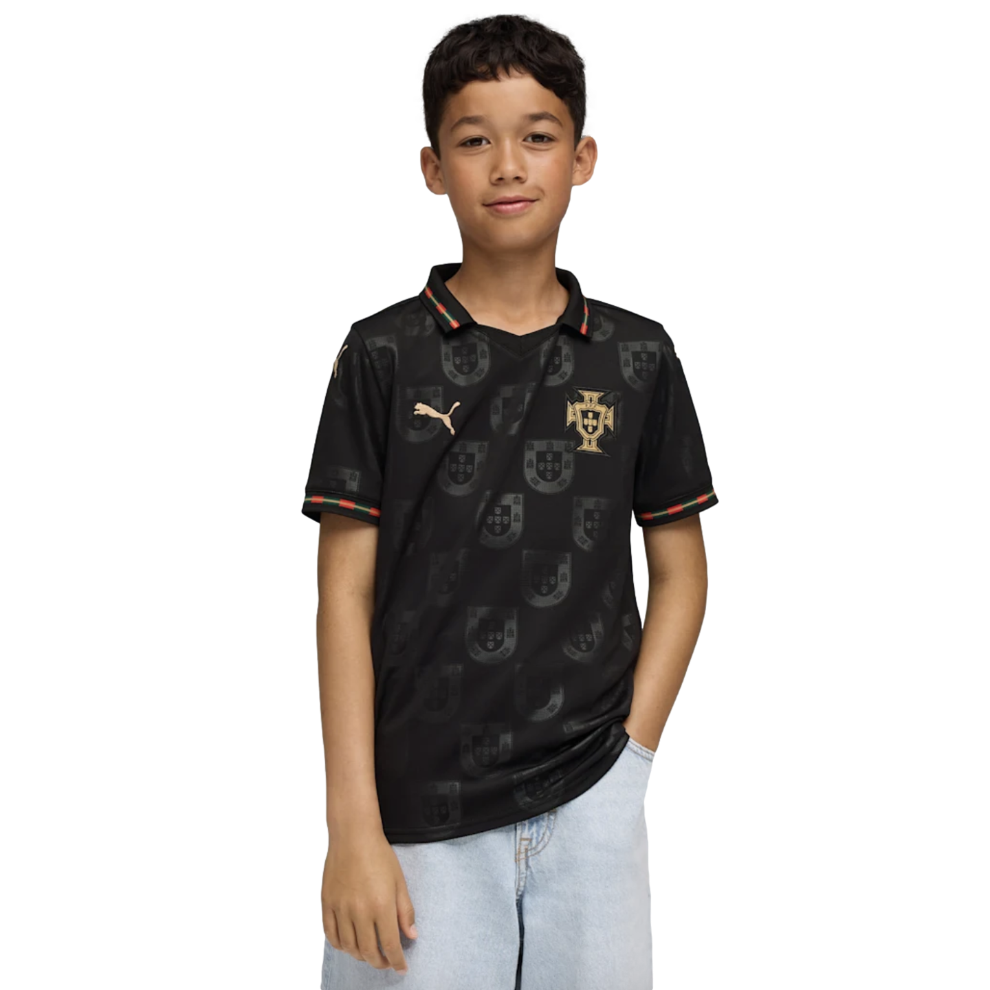 A young boy wearing a black Portugal national team jersey with gold accents and light-blue jeans against a solid black background.