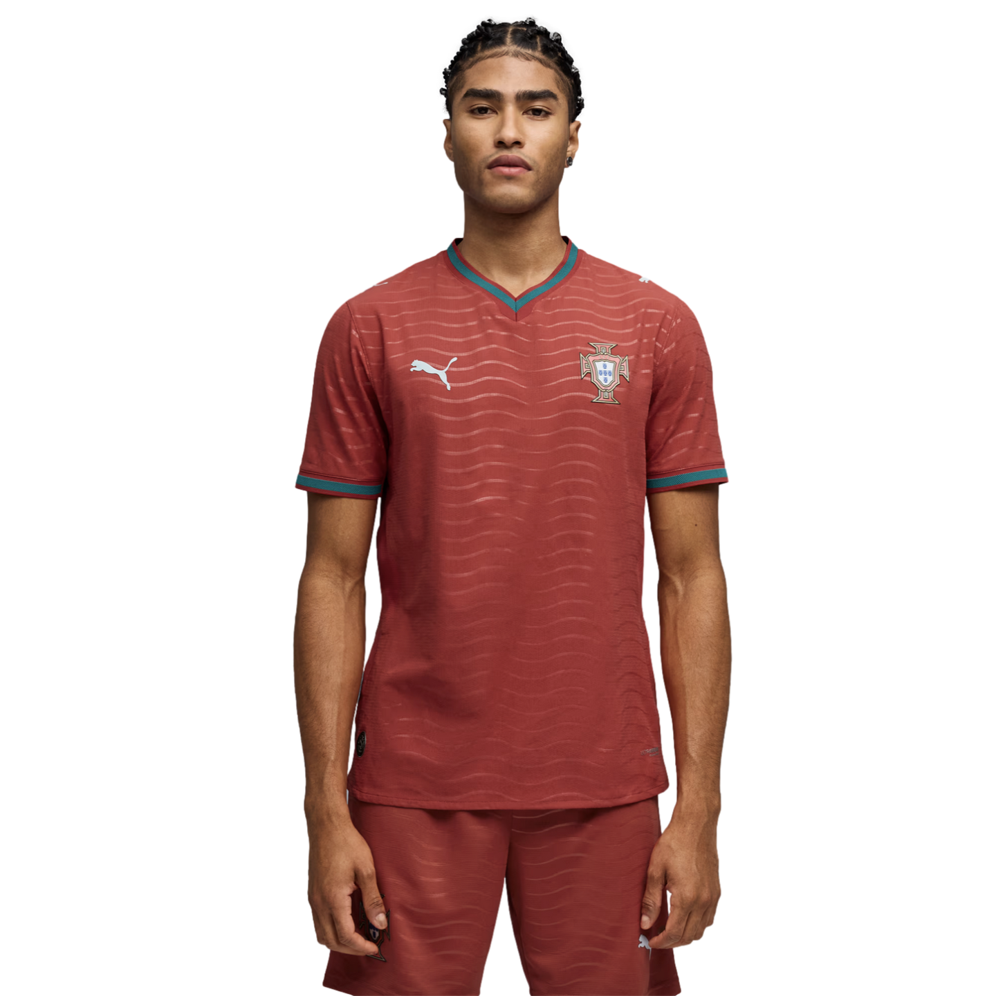 Male model wearing a red Puma football jersey and matching shorts with teal trim and a wavy pattern, standing against a black background.