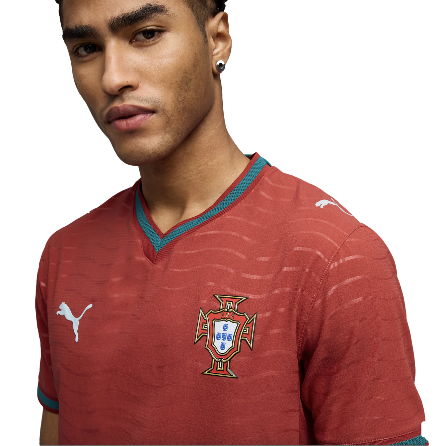 A man wearing a red Puma Portugal football jersey with teal trim and the national team crest, set against a black background.