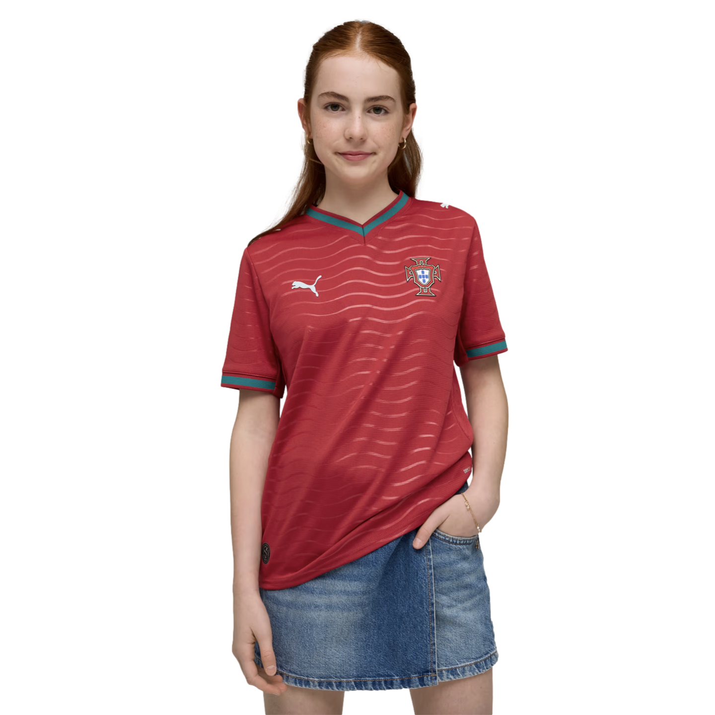 A redheaded woman wearing a red Puma Portugal soccer jersey and a denim skirt against a black background.