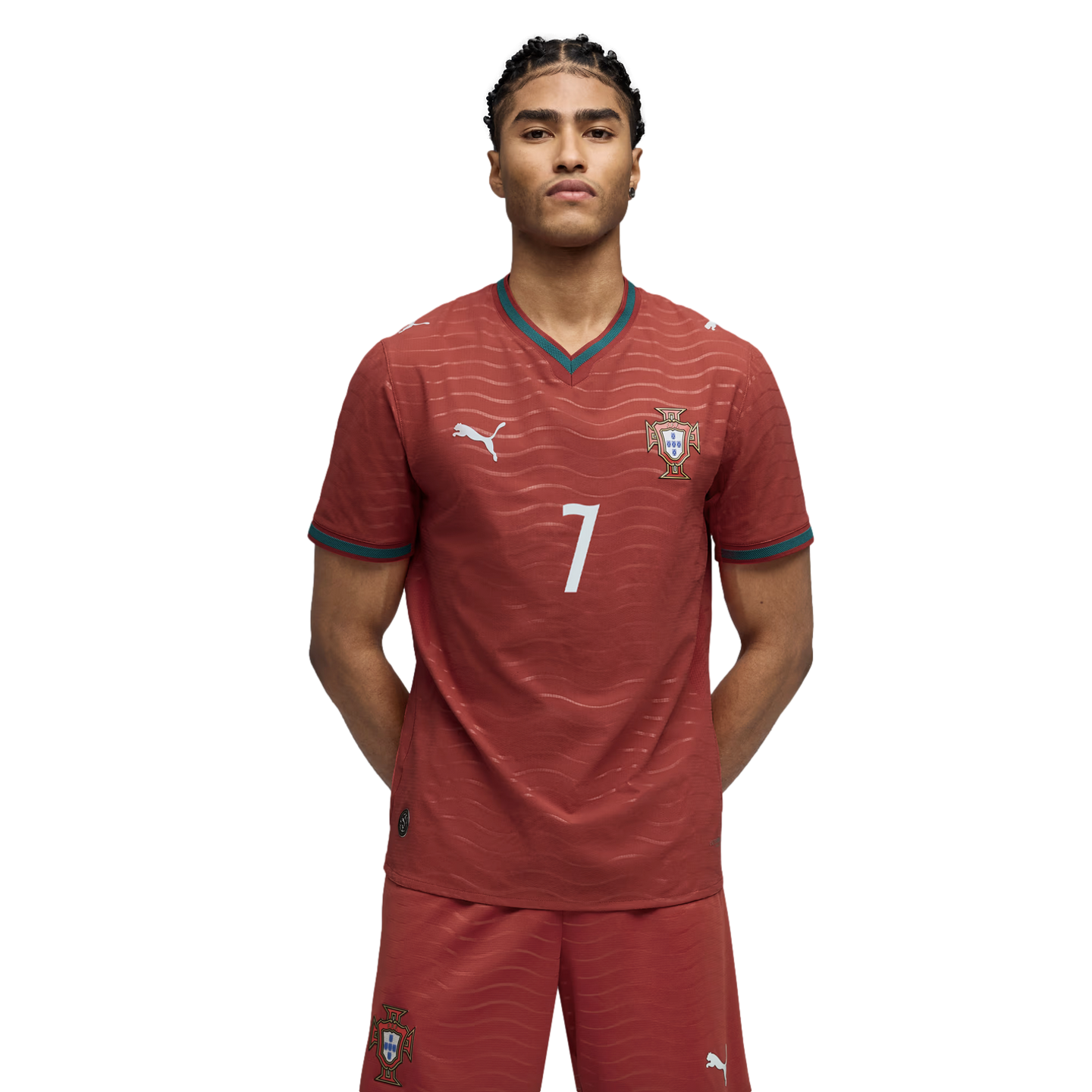 A young man with braided hair wearing a maroon soccer kit with the number 7, standing against a black background.