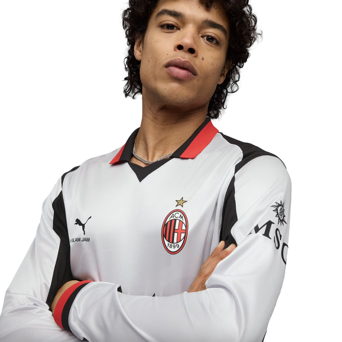 A man wearing a white AC Milan long-sleeve jersey with red and black accents, posing with arms crossed against a black background.