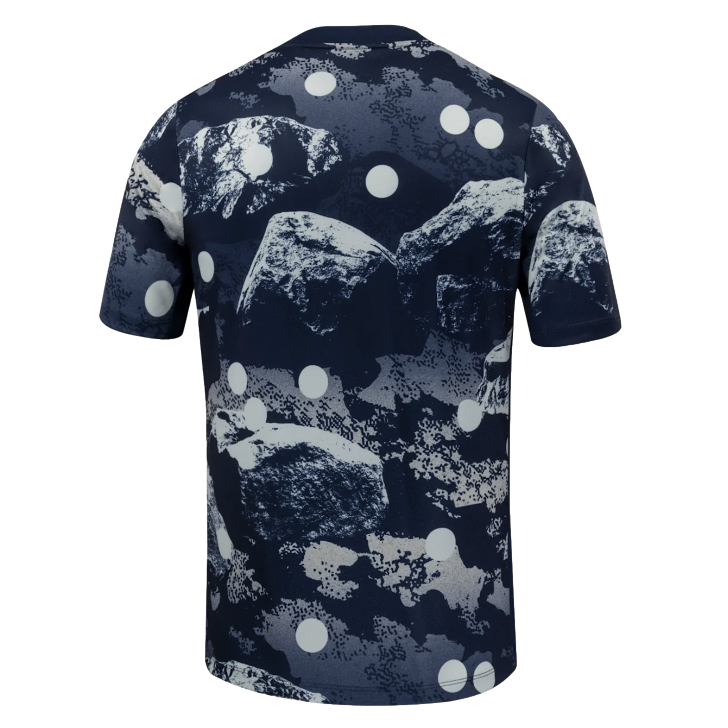 Rear view of a dark blue short-sleeved t-shirt featuring an abstract grey and white rock formation print with white polka dots.