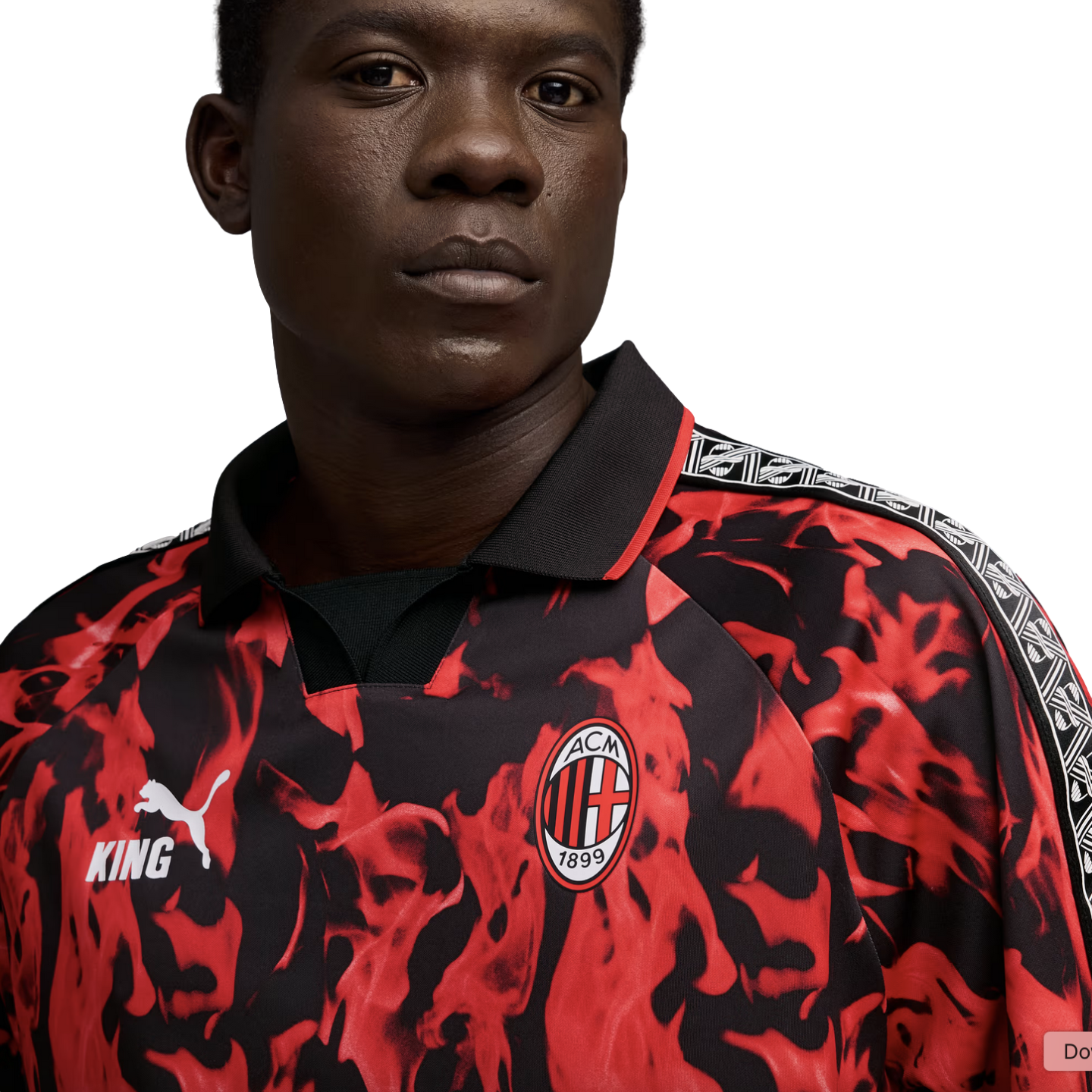 A man wears an AC Milan x Puma King football jersey featuring a red and black flame design, the club crest, and patterned shoulder trim.