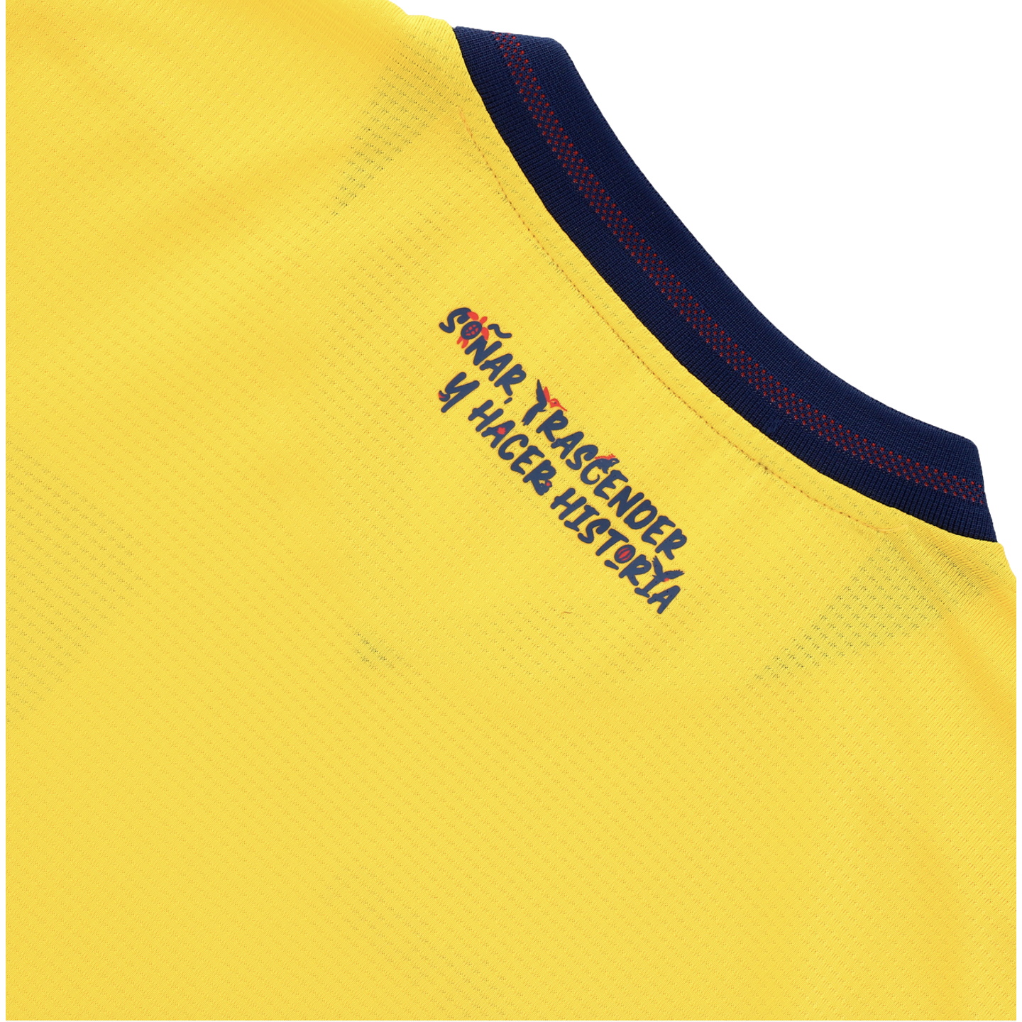 A close-up of a yellow textured fabric garment featuring the Spanish phrase "SOÑAR, TRASCENDER Y HACER HISTORIA" in a blue handwritten style with small red accents. The message is printed near a navy blue collar with a red dotted pattern.
