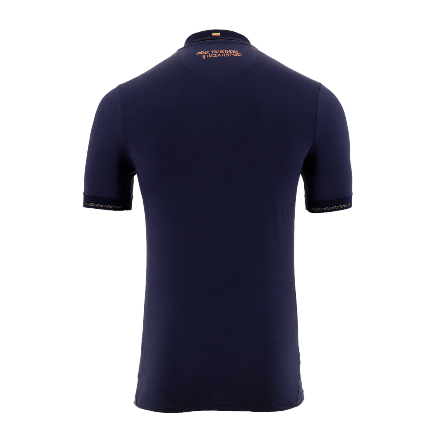 A back view of a navy blue short-sleeved soccer jersey against a solid black background. Near the collar, there is a small Colombian flag above the copper-colored Spanish text, "SOÑAR TRASCENDER Y HACER HISTORIA." The sleeve cuffs are accented with a matc