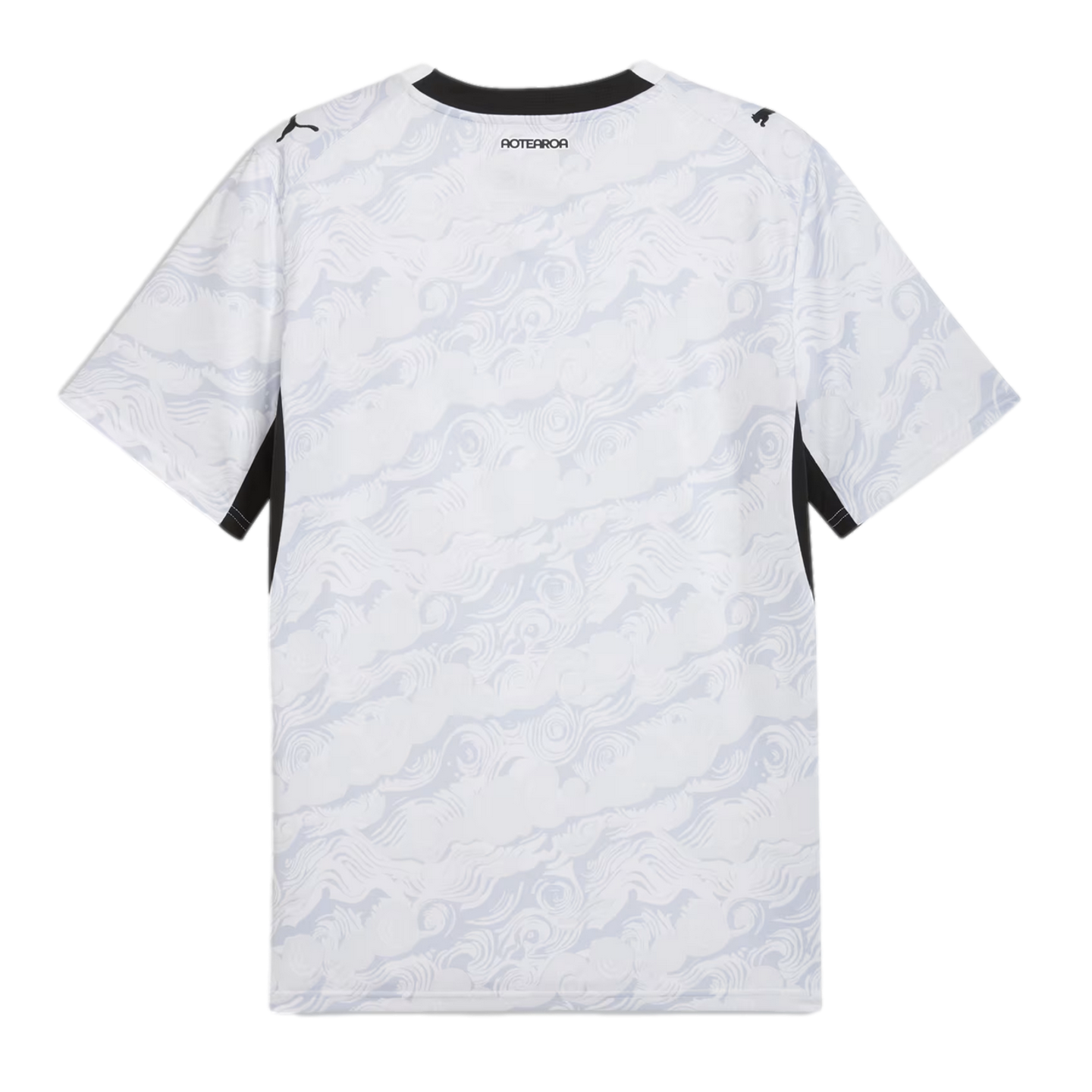 A back view of a white Puma sports jersey featuring a subtle, light gray swirling wave pattern across the entire garment. The shirt has a black crew neckline, black Puma logos on each shoulder, and the word "AOTEAROA" printed in black on the upper back.