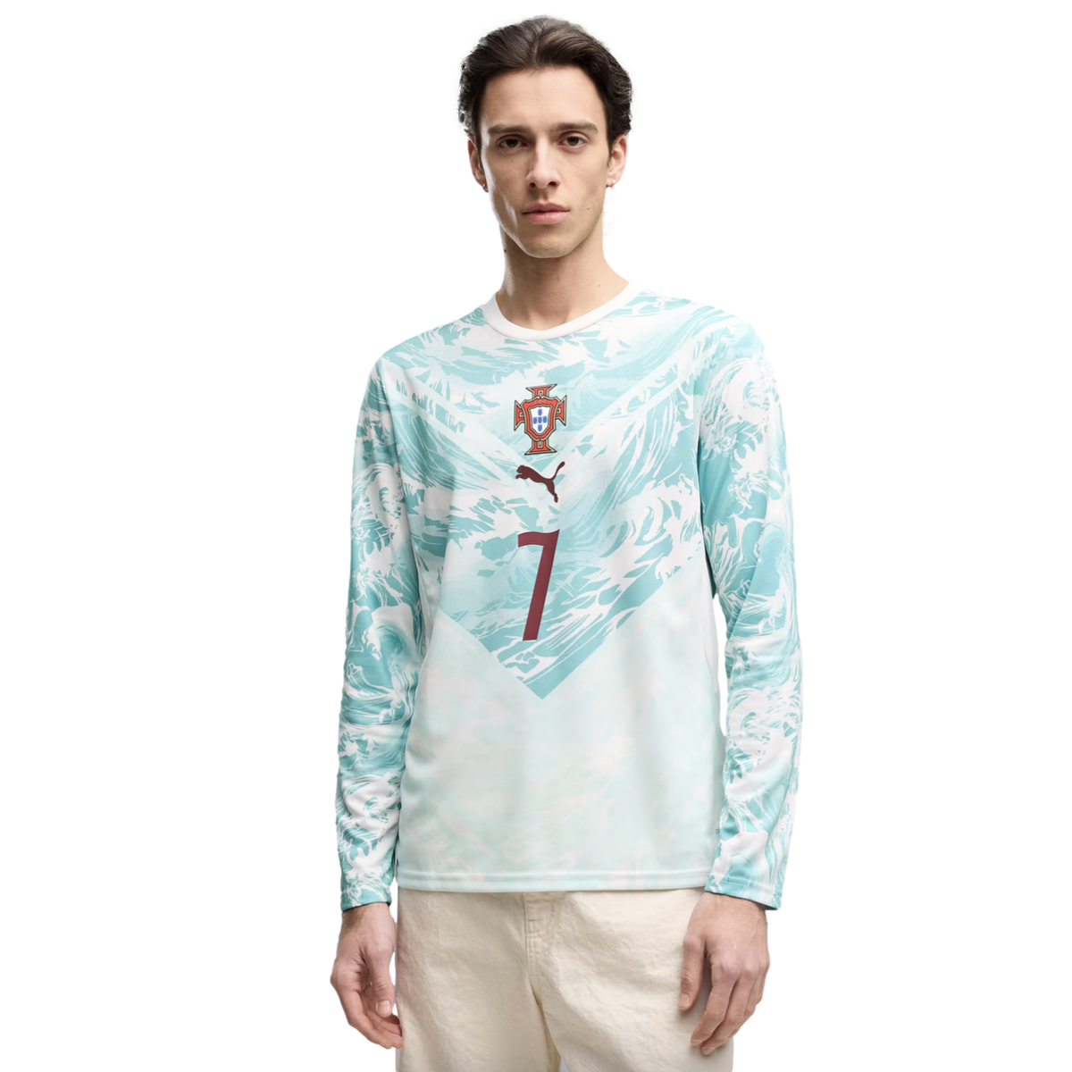 A young man stands against a black background wearing a light blue and white wavy-patterned long-sleeved shirt. The shirt features the Portugal national team crest, a brown Puma logo, and a large brown number 7 on the front.