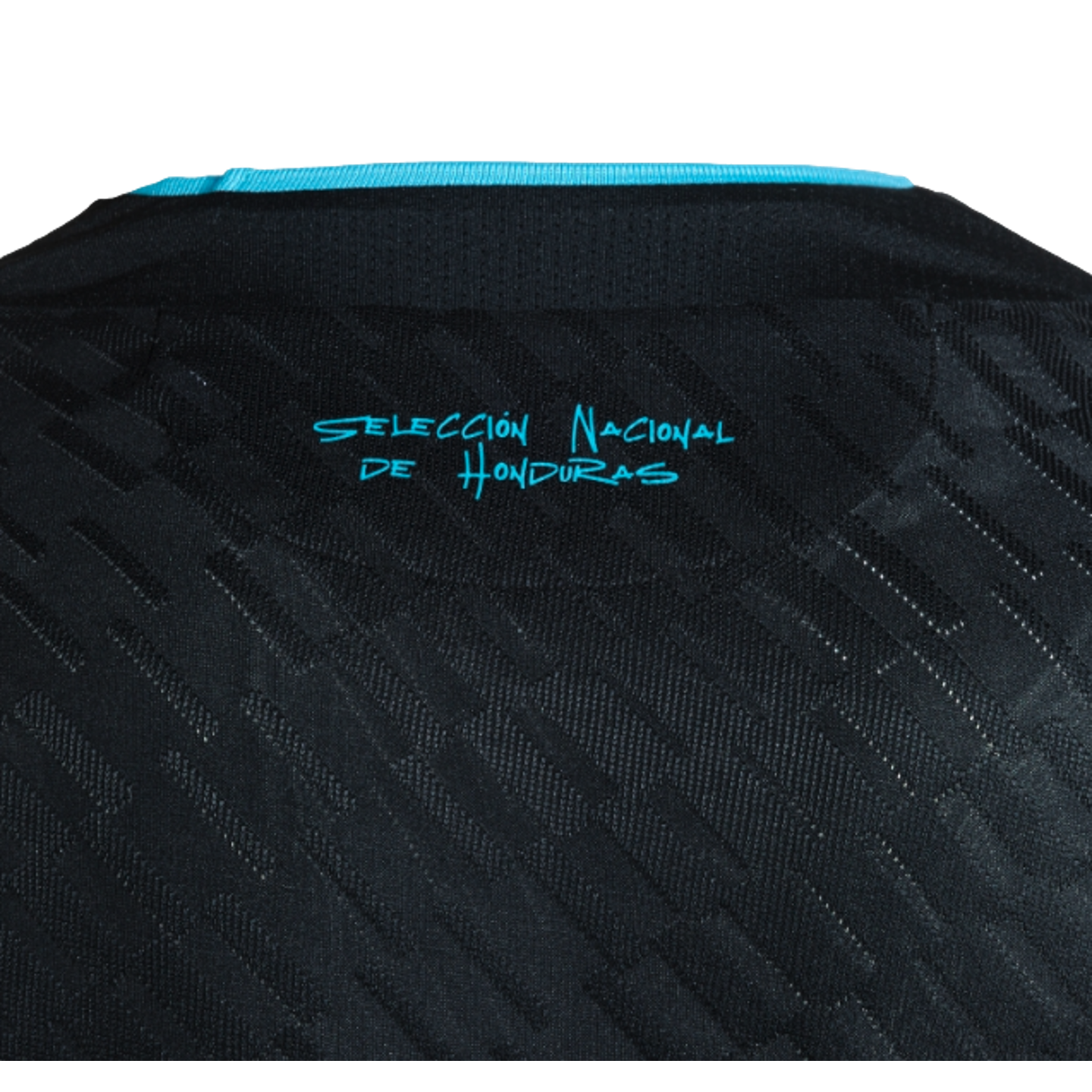 A close-up of the upper back of a black textured jersey, featuring a turquoise trim at the collar and the words "SELECCIÓN NACIONAL DE HONDURAS" printed in stylized turquoise text.