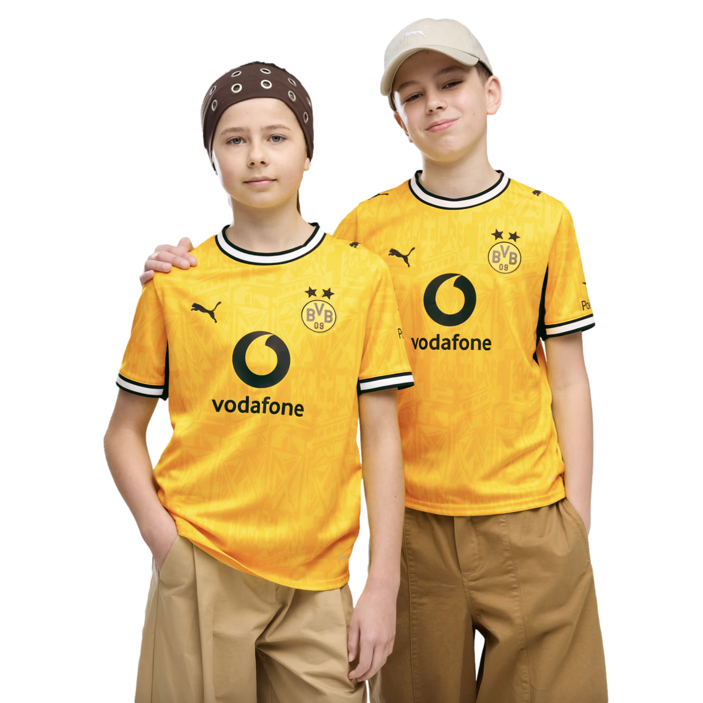 Two young people pose side-by-side in matching yellow Borussia Dortmund soccer jerseys against a black background. One wears a brown bandana and the other a beige baseball cap.
