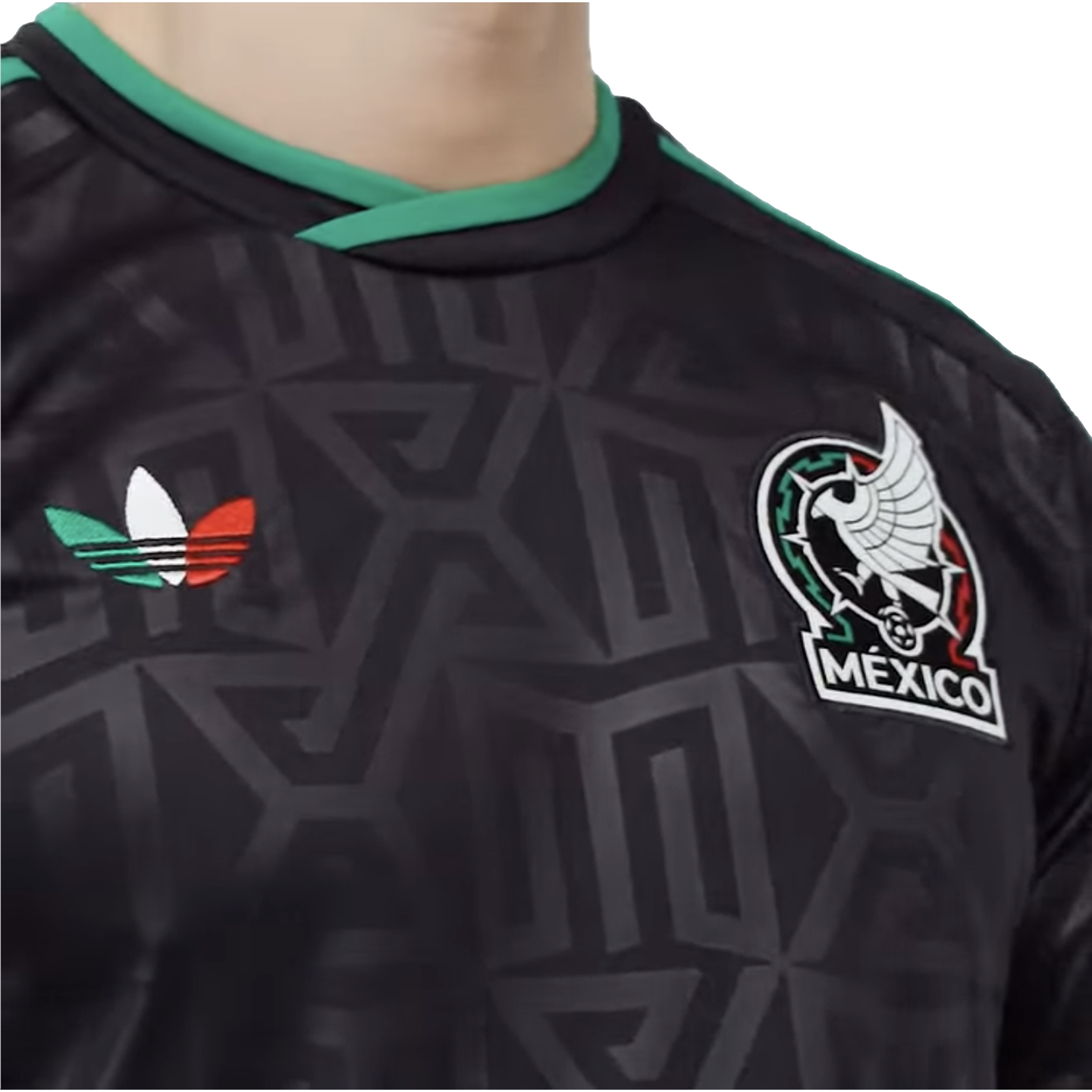 Close-up of a black Mexico national football team jersey with a subtle geometric pattern, featuring the team crest and a green, white, and red Adidas trefoil logo.