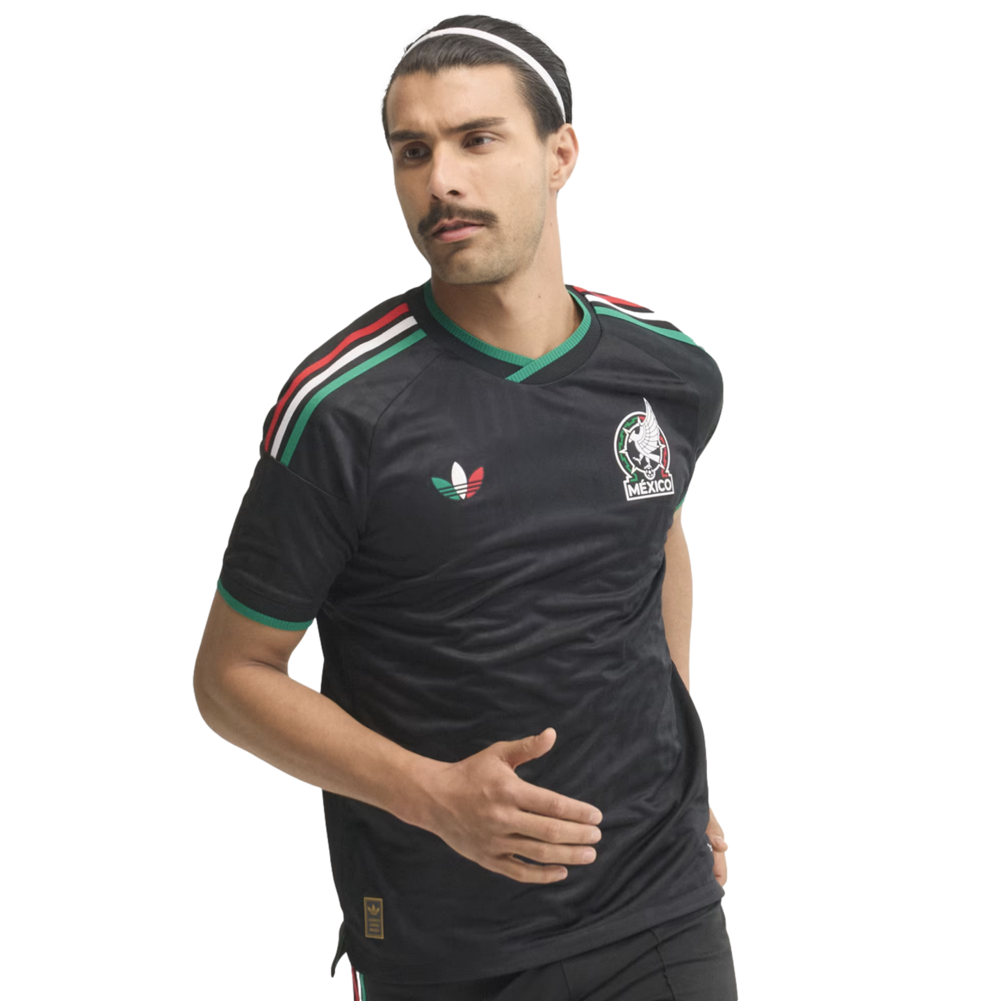A man with a mustache in a running pose wears a black Mexico national team soccer jersey and a white headband against a white background.