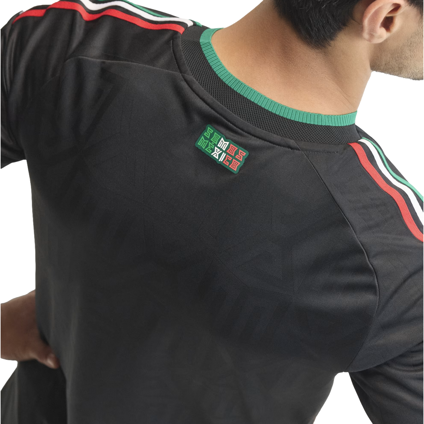 Back view of a black sports jersey with green, white, and red stripes on the shoulders and a "SOMOS MÉXICO" patch at the neck.