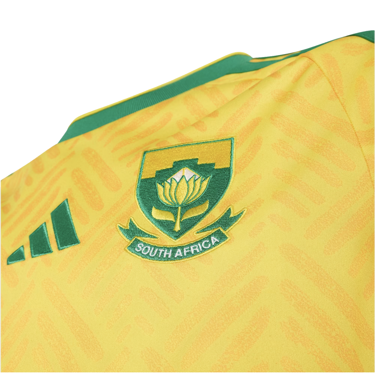 Close-up of a yellow South Africa sports jersey with a green embroidered crest featuring a King Protea flower and "SOUTH AFRICA" text.