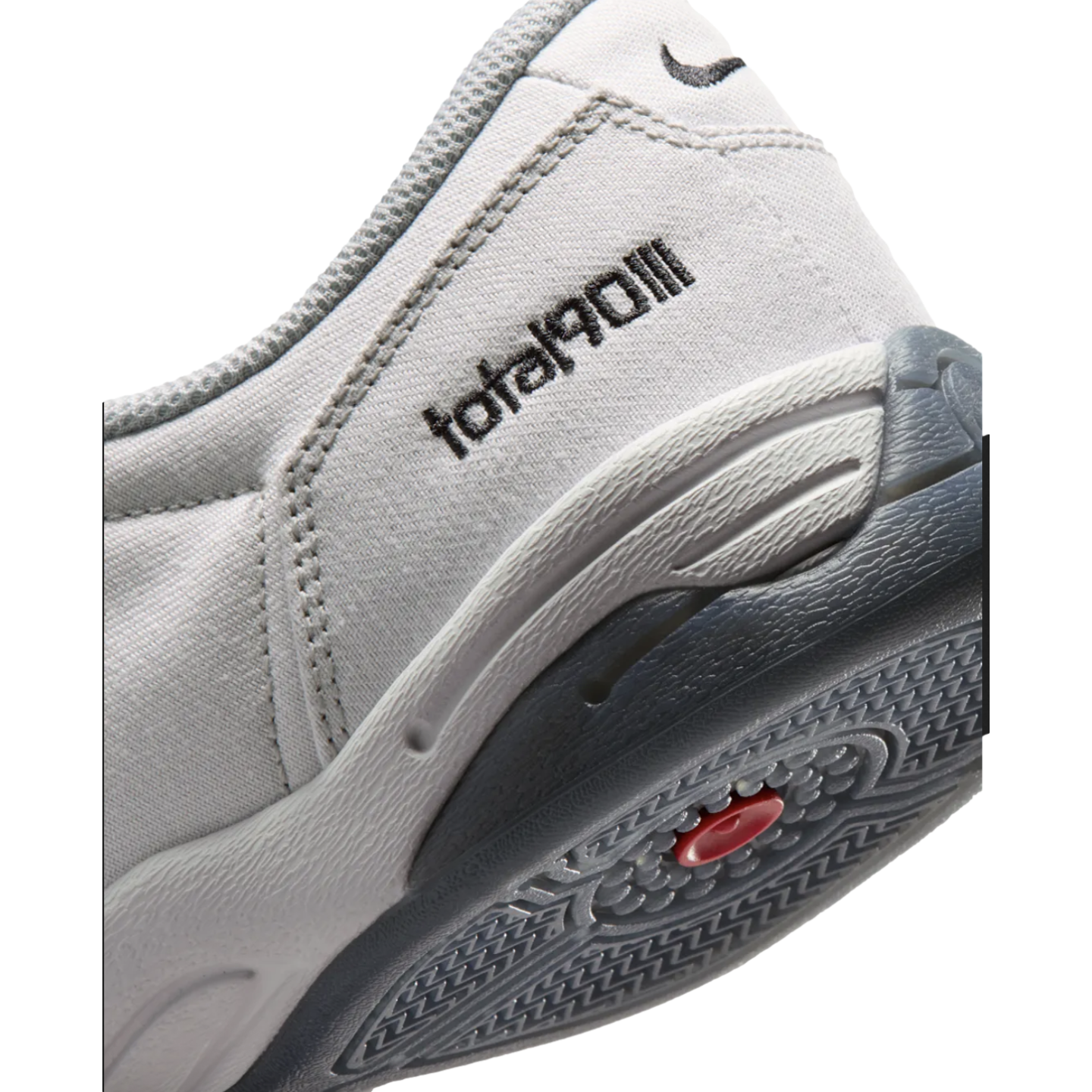 Close-up of a grey Nike Total 90 III shoe's heel featuring the "total90III" logo, a small swoosh, and a textured grey and black sole with a red accent.