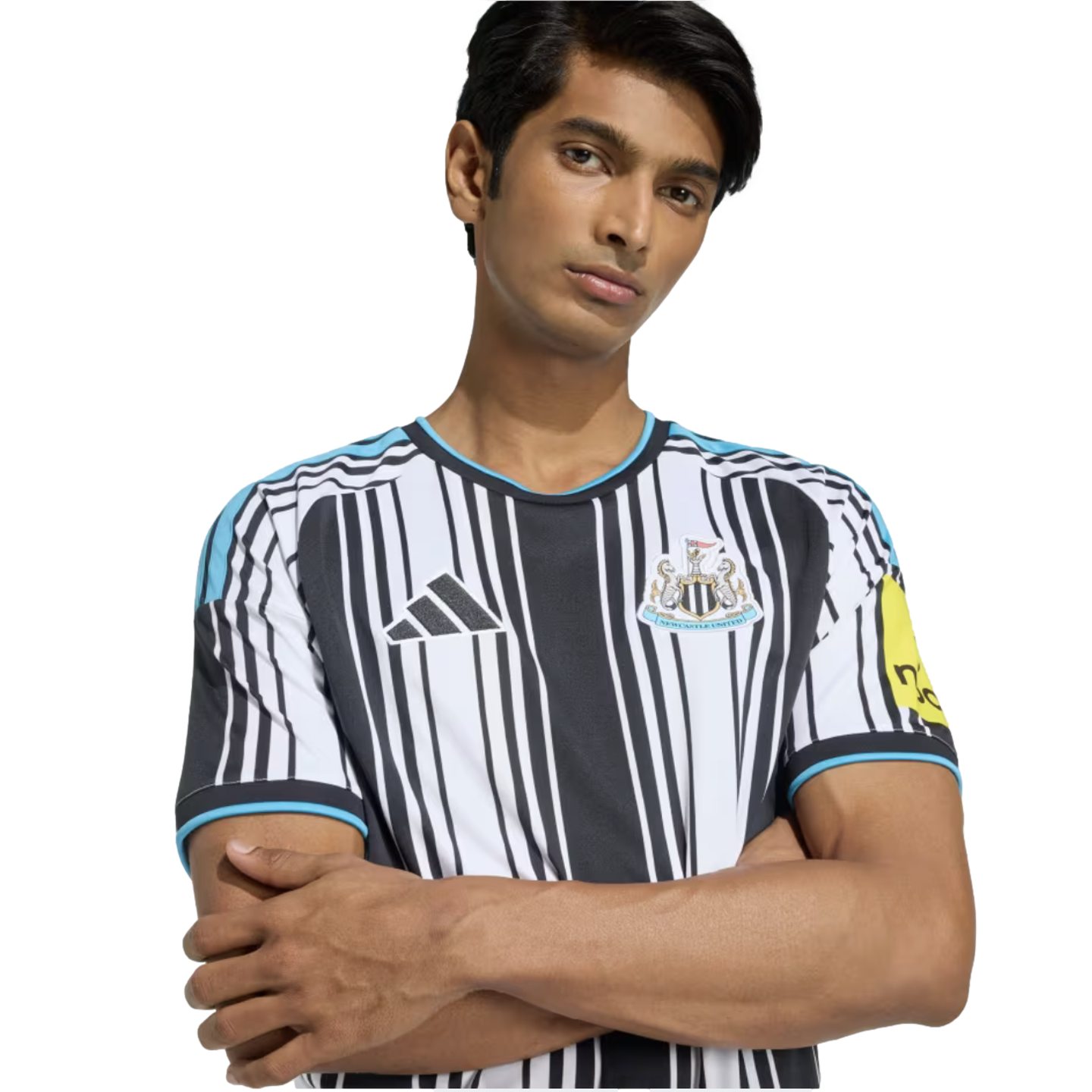 A man posing with arms crossed in a black and white striped Adidas Newcastle United soccer jersey.