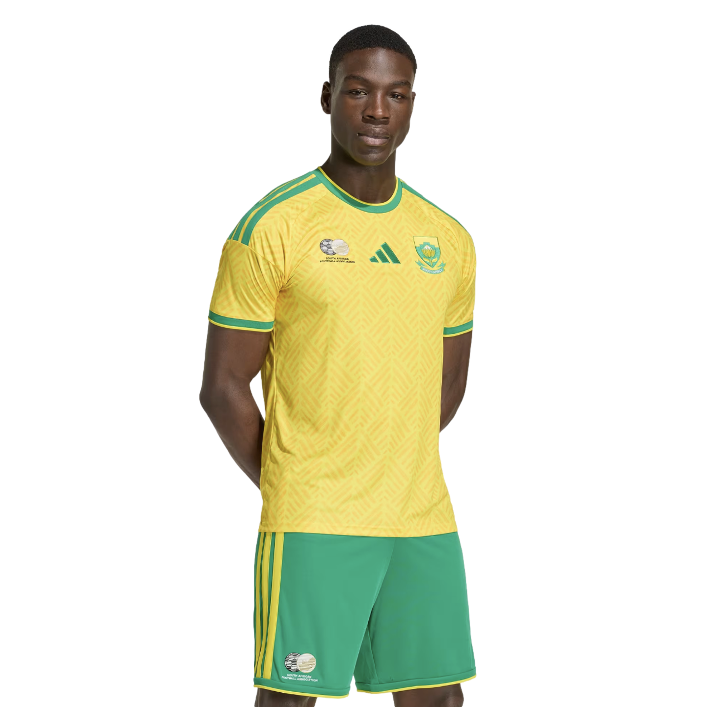 A man models the yellow and green Adidas South Africa national football team kit against a plain white background.