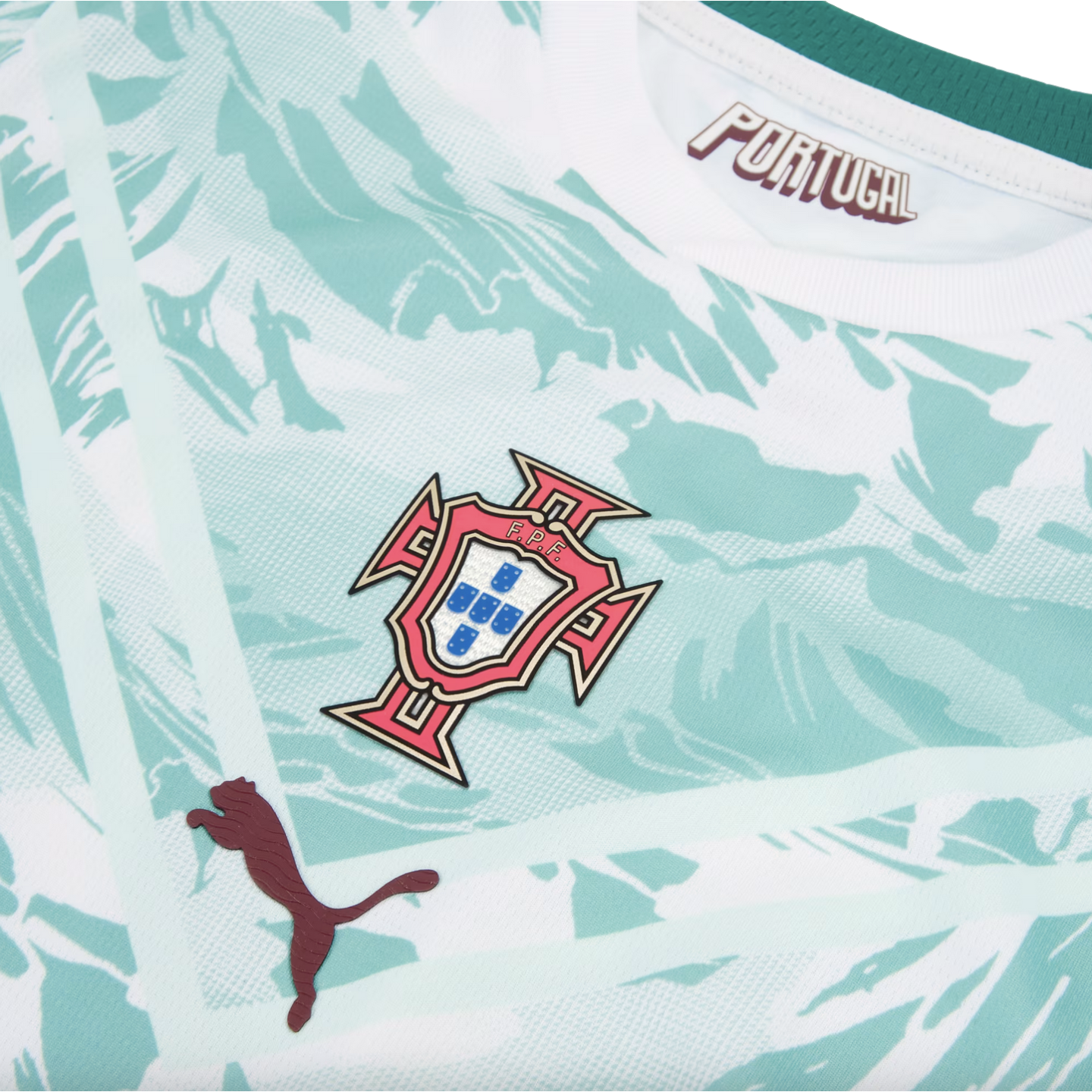 A close-up of a Portugal national football team jersey, featuring a light mint green and white marbled pattern. The central focus is the Portuguese Football Federation (FPF) crest. A dark red Puma logo is positioned to the bottom left, and the word "PORTU