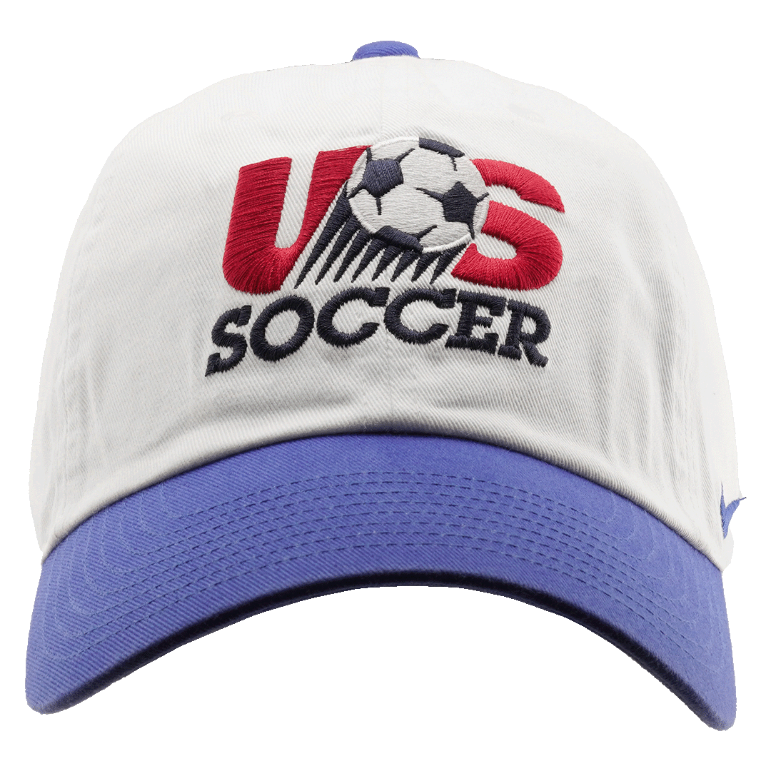 A white baseball cap with a blue brim and an embroidered US Soccer logo featuring a soccer ball. A small blue Nike swoosh is on the side.
