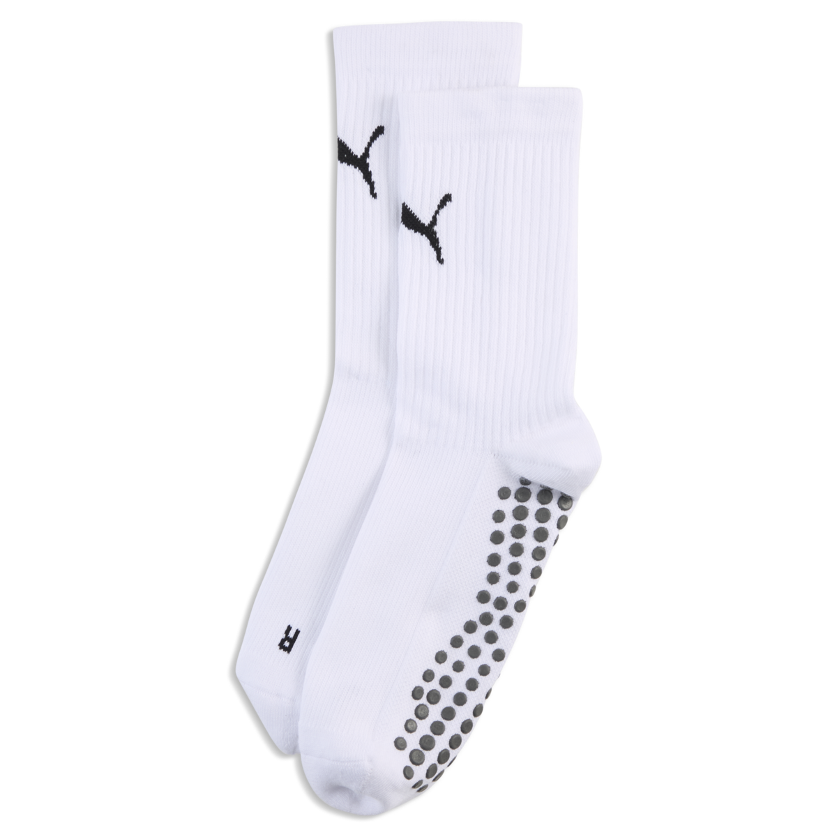White Puma crew socks with black logos on the ankles and grey non-slip grippers on the soles, against a black background.