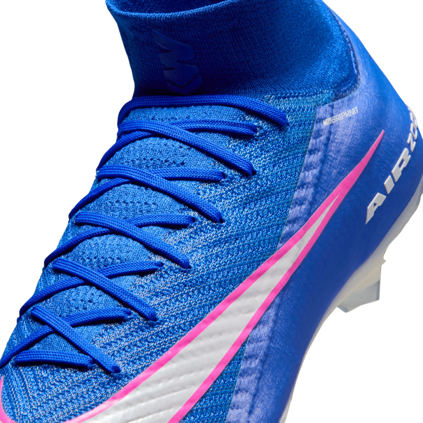 A close-up of a blue Nike soccer cleat with pink and white accents, blue laces, and a textured upper against a black background.