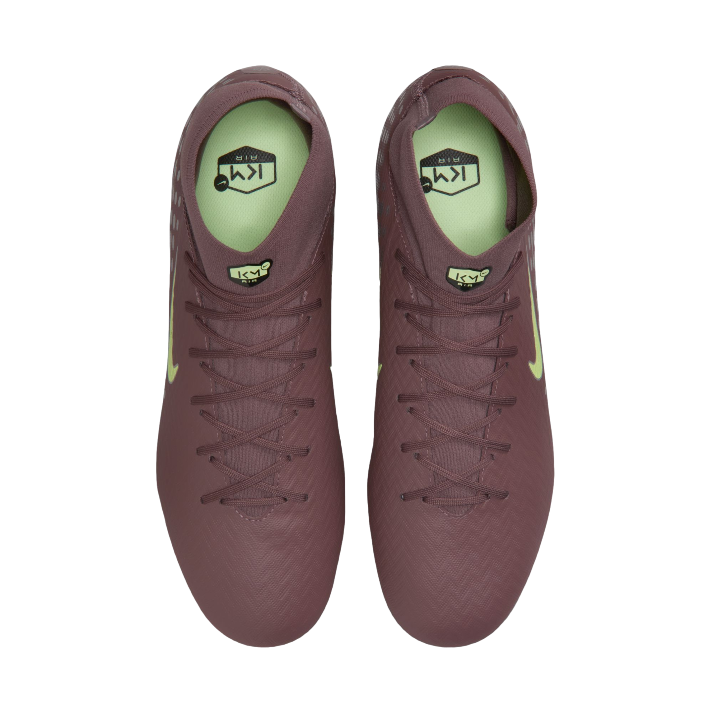 Top-down view of a pair of mauve Nike soccer cleats with neon green accents and "KM" branding on a black background.
