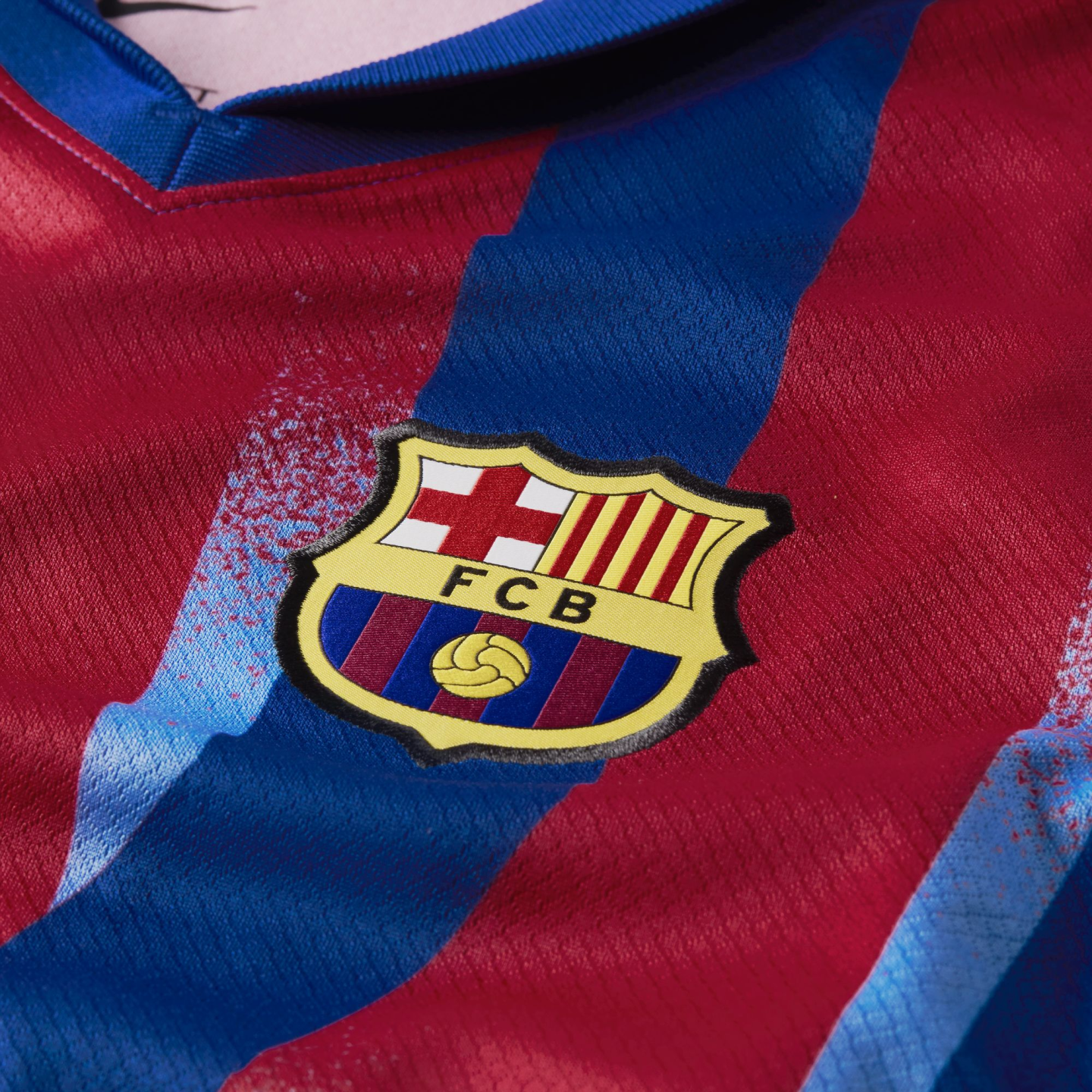 Close-up of an FC Barcelona soccer jersey featuring the embroidered club crest over red and blue vertical stripes.