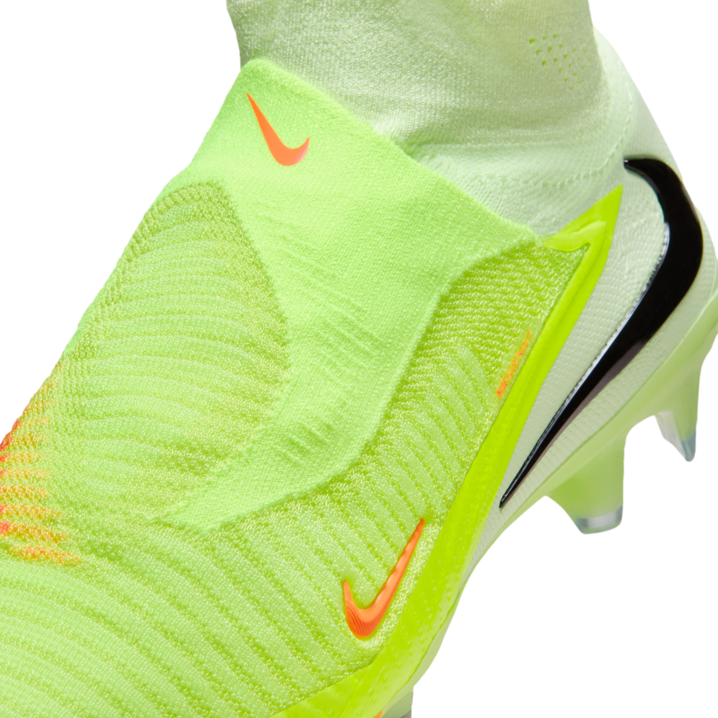 Close-up of a neon green laceless Nike soccer cleat with a textured knit upper and orange and black Nike swoosh logos.