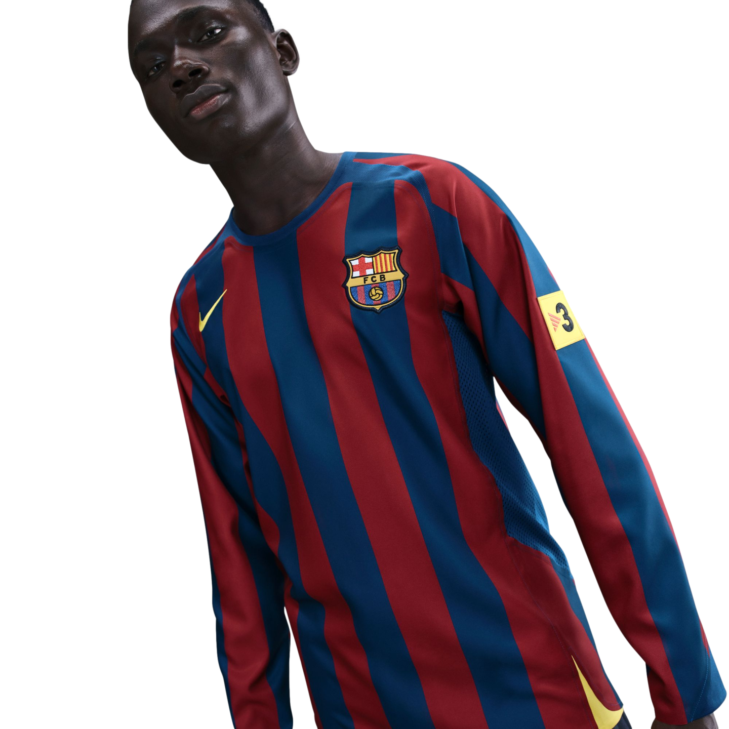 A man wearing a long-sleeved red and blue striped FC Barcelona jersey against a black background.