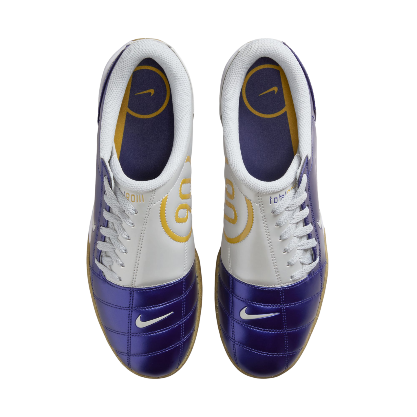 Top-down view of a pair of purple and white Nike Total 90 indoor soccer shoes with yellow accents, white laces, and gum outsoles.